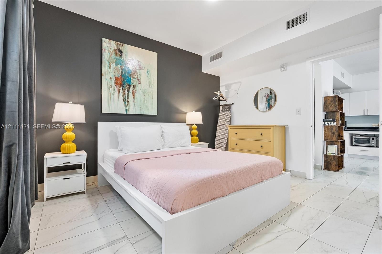 Large-format white tile flooring with veining detail and a distinct charcoal-colored accent wall