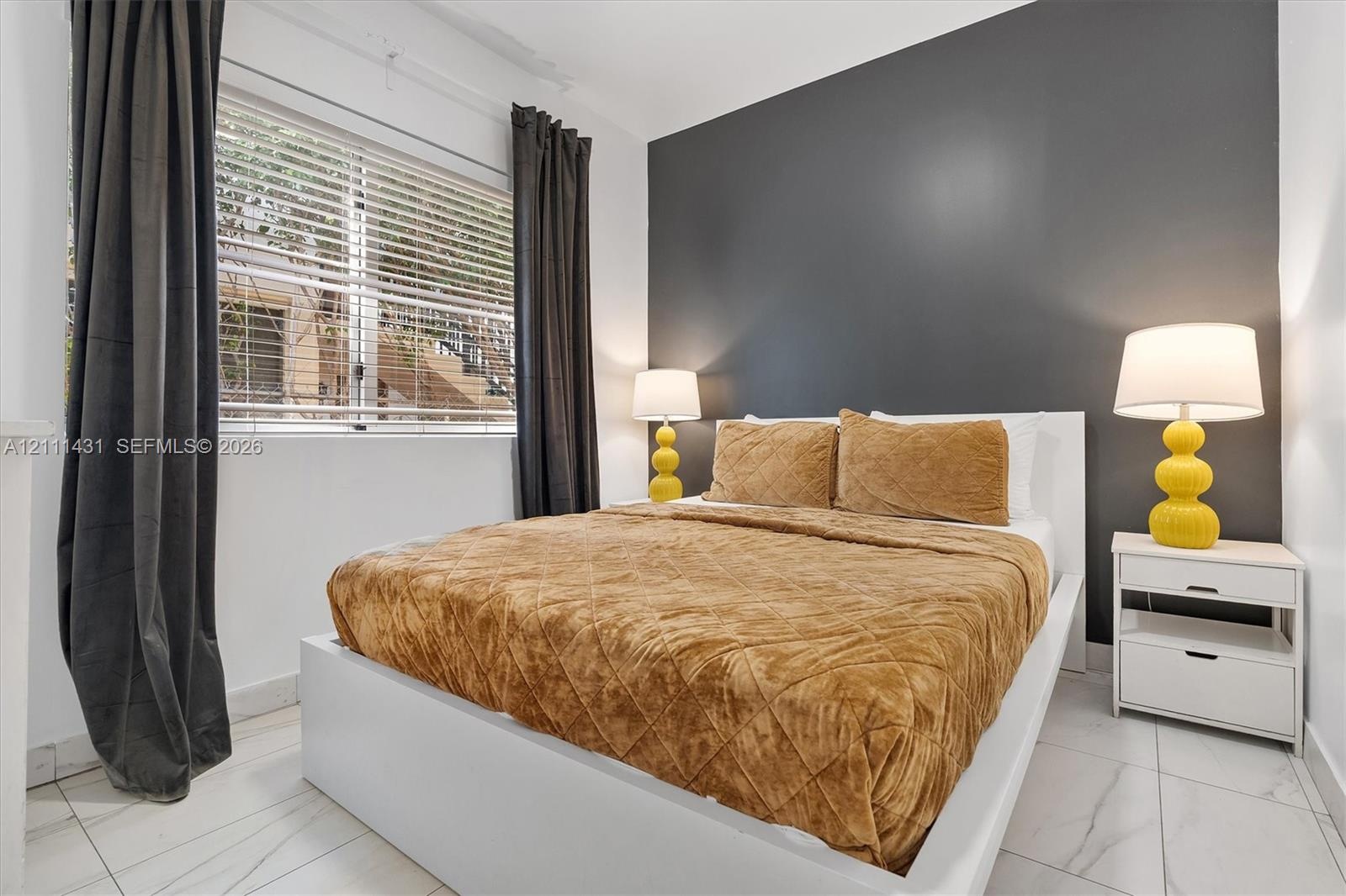 Neutral-toned room featuring a dark charcoal accent wall, large format tile flooring, and a multi-pane horizontal window