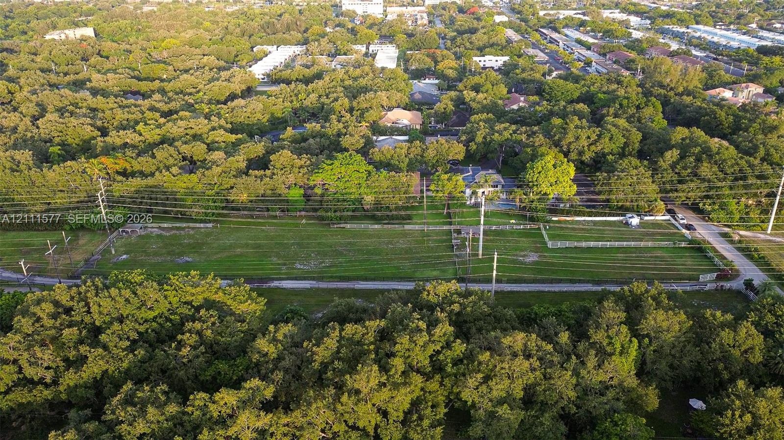 Expansive rectangular parcel featuring open terrain, mature perimeter trees, and a paved road frontage