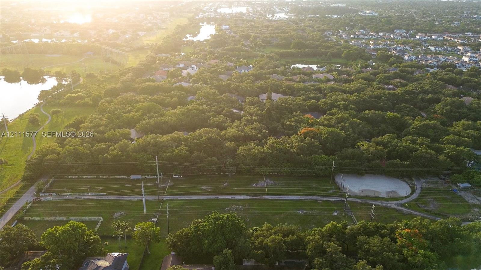 Aerial perspective of a sprawling parcel featuring expansive green space, mature tree canopy, and established landscaping