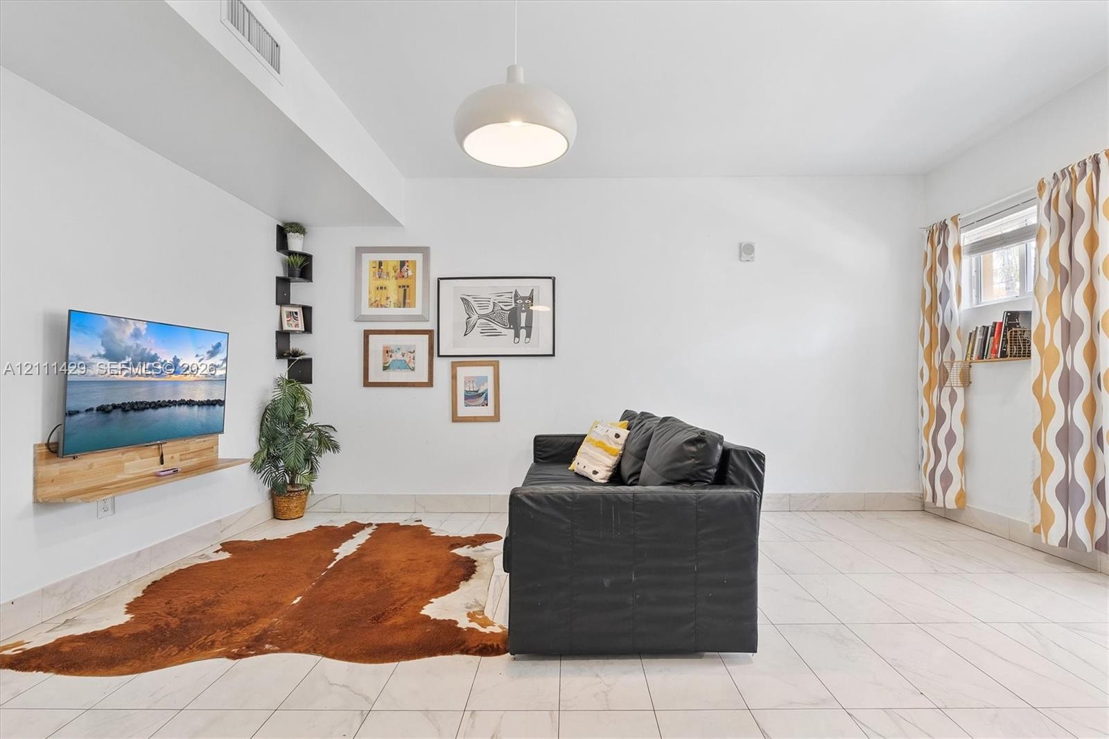 Neutral tile flooring, custom floating wood-finish media console, built-in corner display shelving, and modern dome pendant lighting