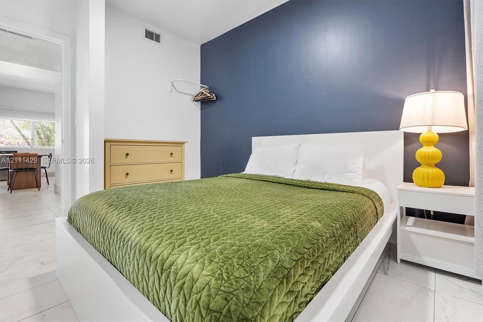 Room featuring light-toned tile flooring and a bold navy accent wall