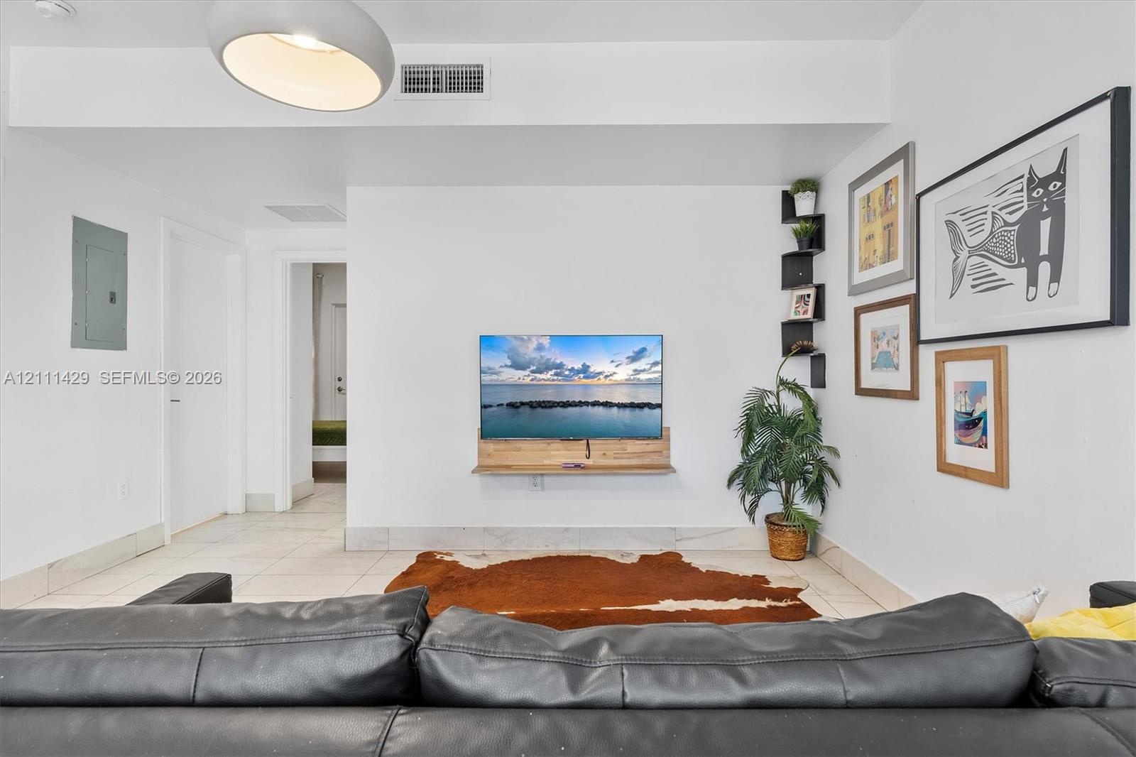 Living space featuring large-format tile flooring, a wall-mounted floating wood shelf, and black corner-mounted shelving
