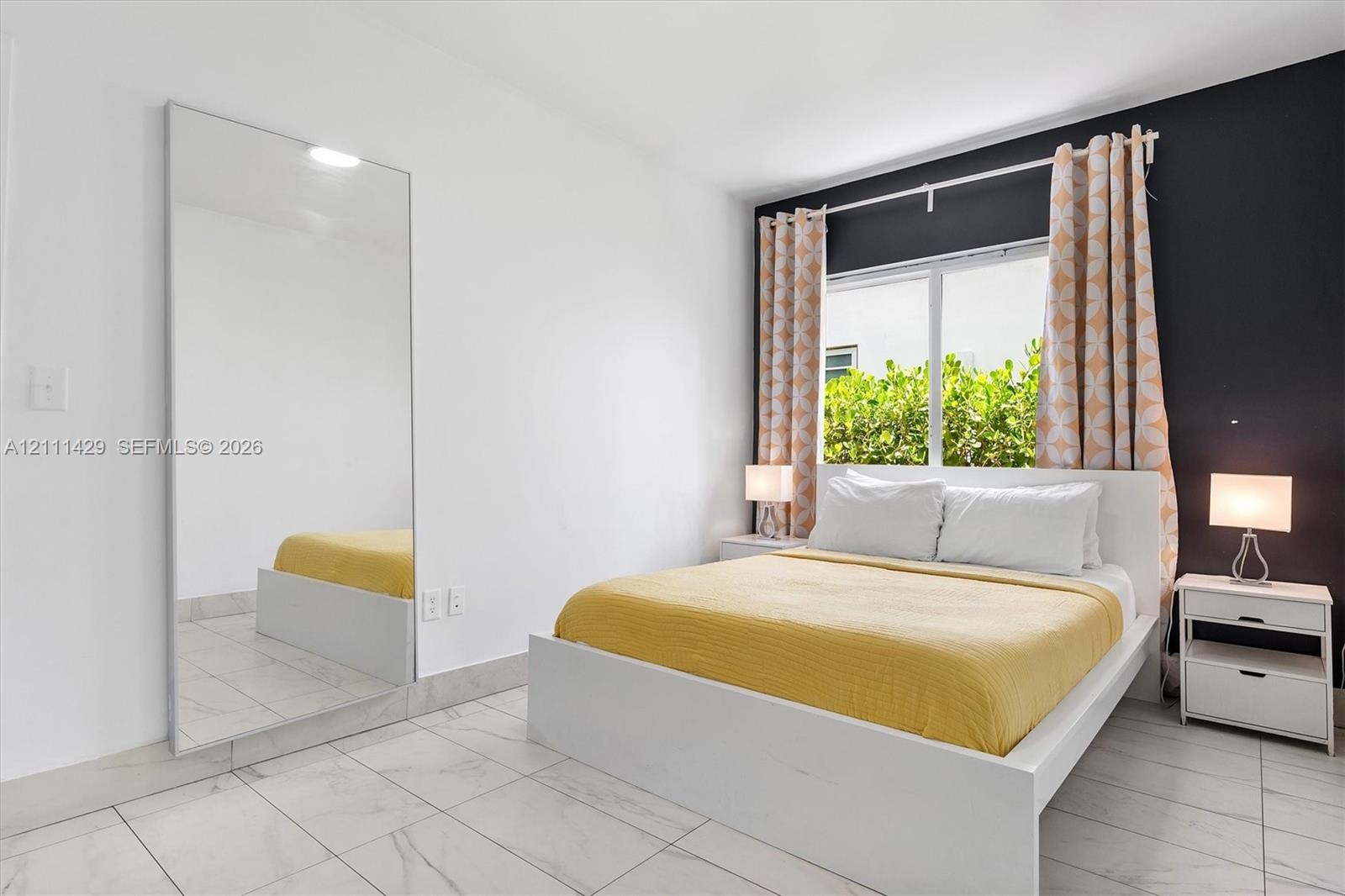 Full-height wall mirror, light-toned stone-finish tile flooring, and a bold dark accent wall