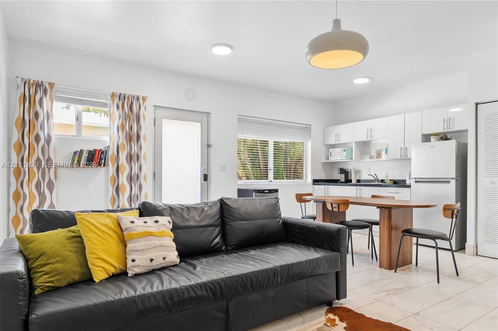 Open-concept space featuring tile flooring, white cabinetry, a built-in wall shelf, flush-mount ceiling lighting, and a dome pendant fixture