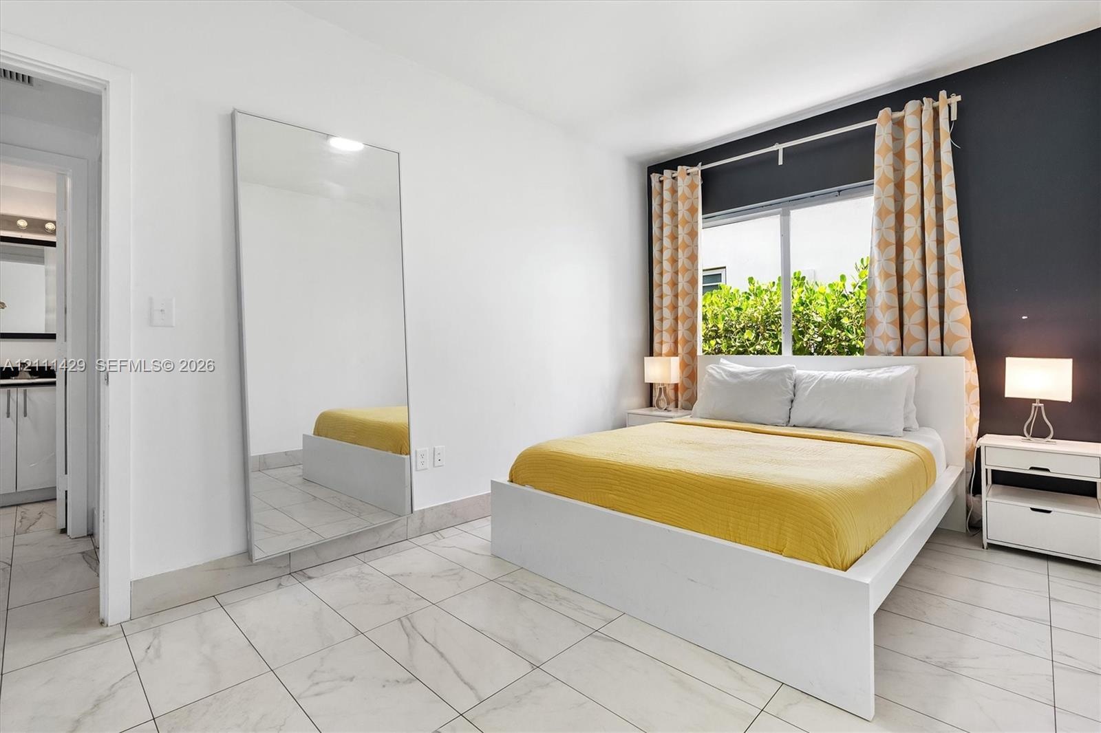 Neutral-toned tile flooring, large-format mirror with sleek framing, and an accent wall featuring a dark finish