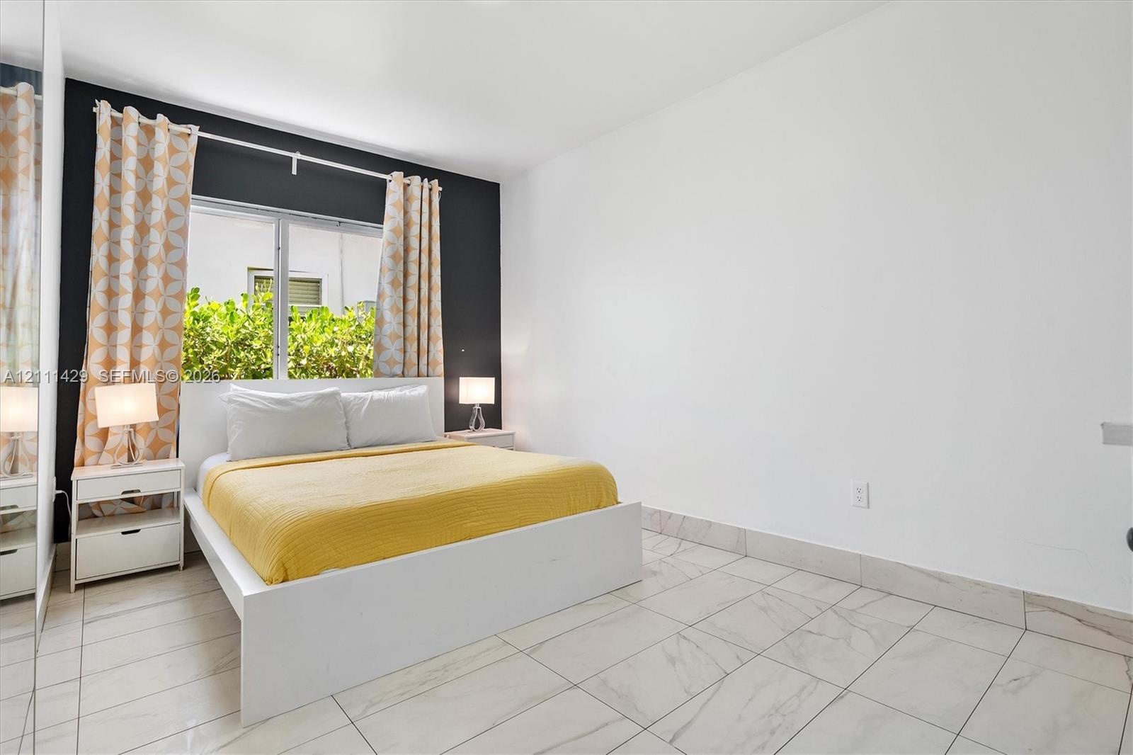Neutral-toned ceramic tile flooring, full-height mirrored closet, and a bold accent wall