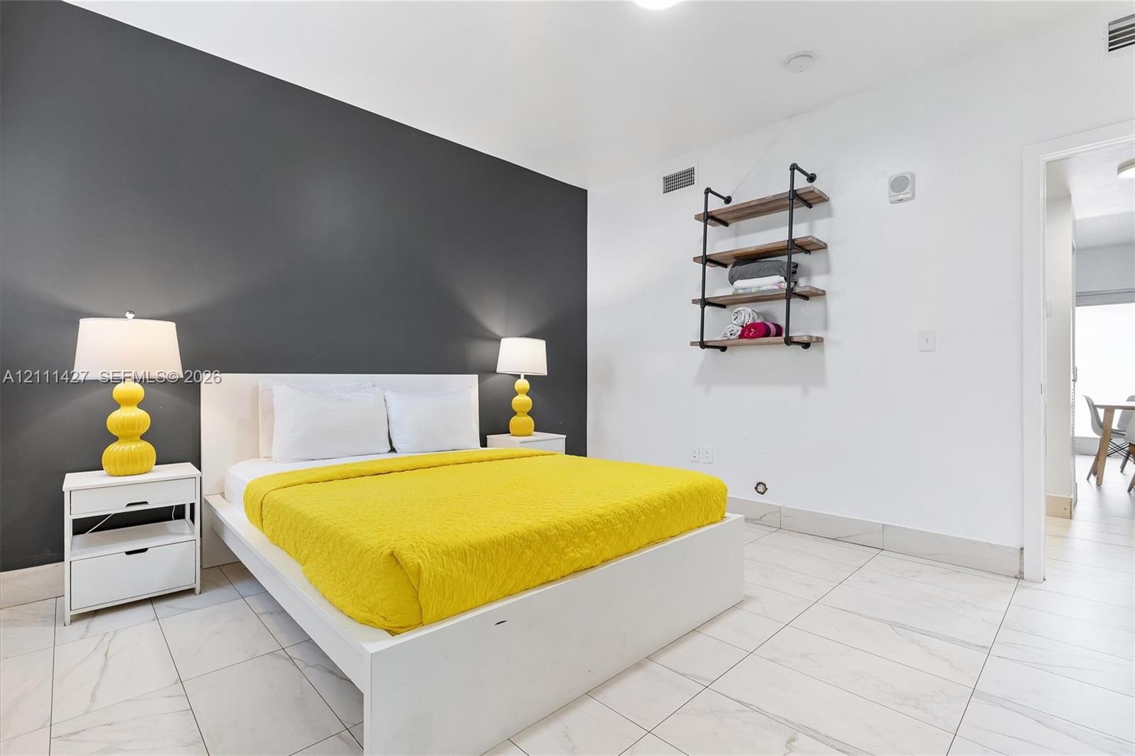 Large-format tile flooring, bold dark accent wall, and wall-mounted industrial-style shelving with wood-finish planks and black metal piping