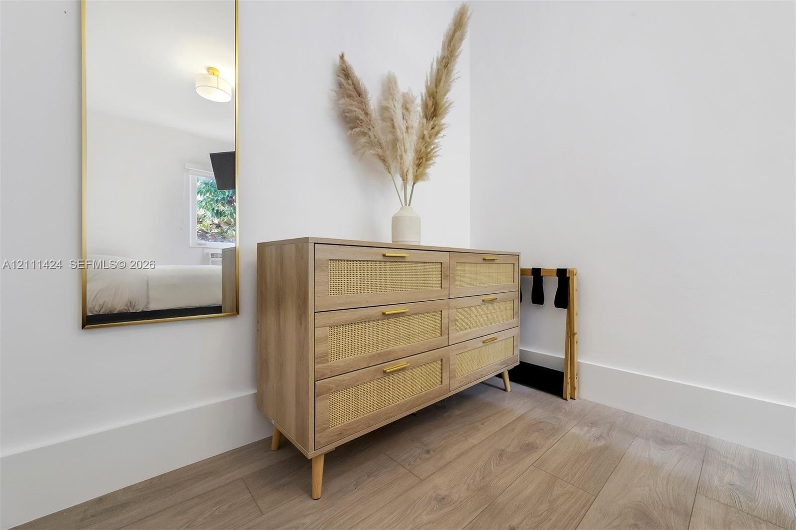 Wood-finish flooring and wall-mounted gold-rimmed mirror