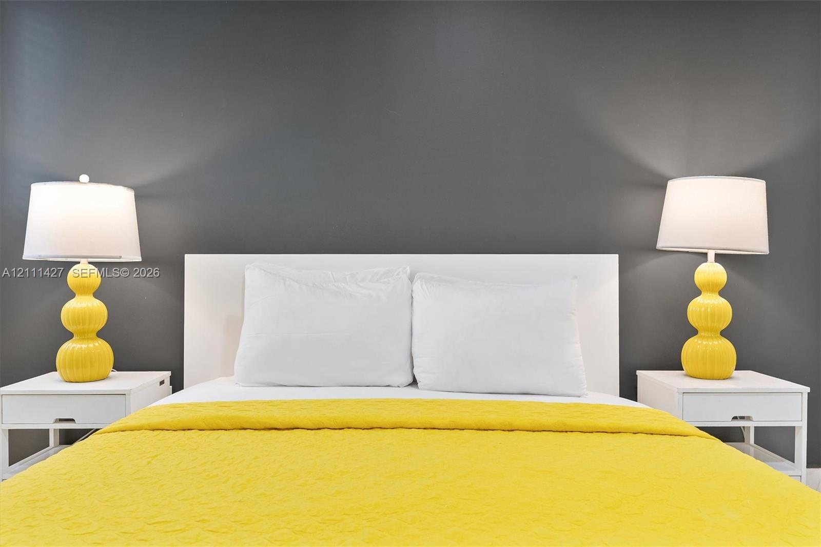 Charcoal-painted accent wall featuring a minimalist white headboard