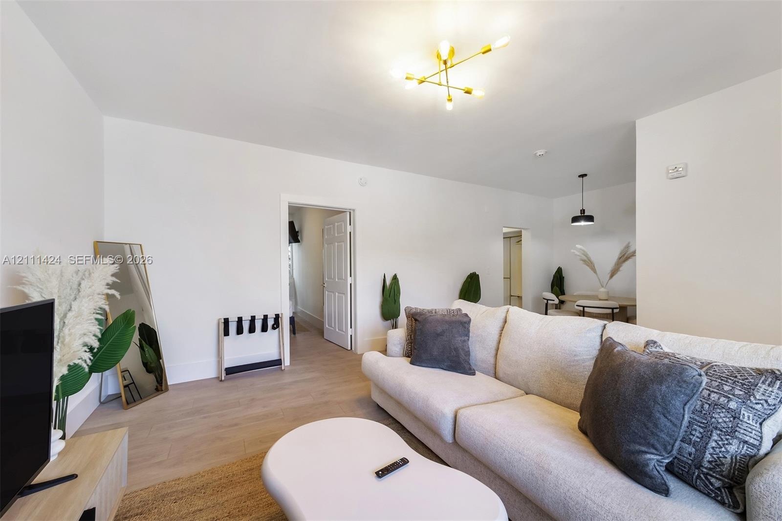 Neutral-toned wood-finish flooring, multi-arm gold-tone chandelier, and recessed ceiling lighting