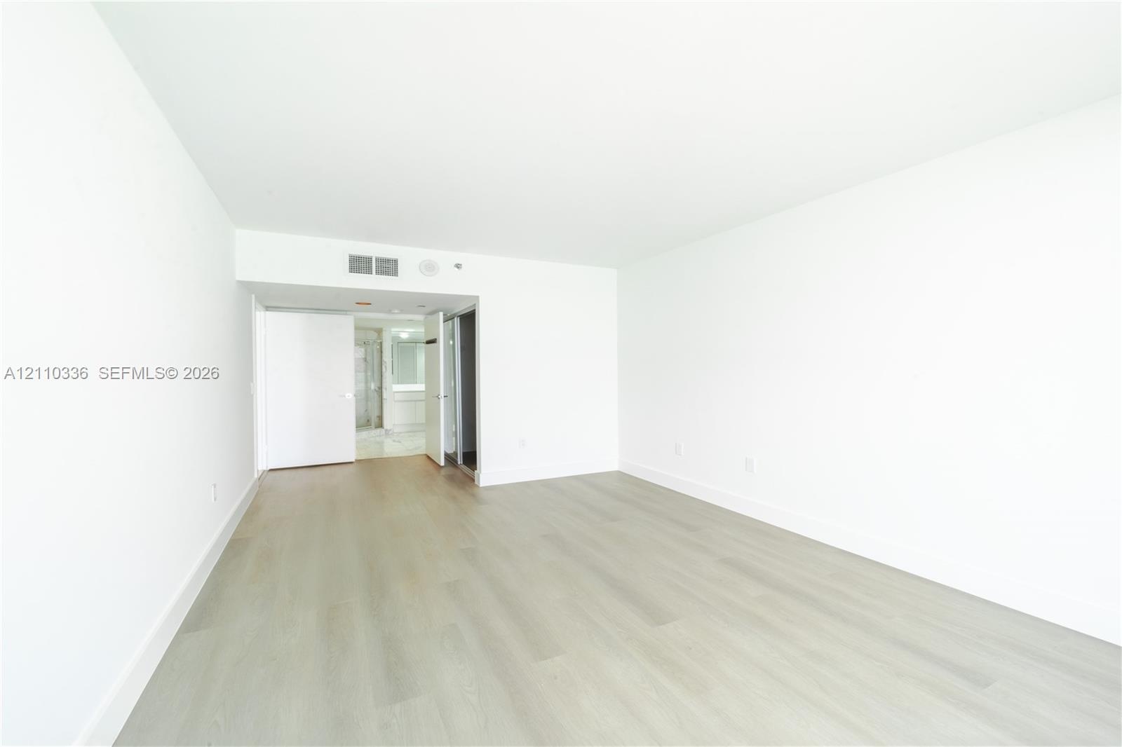 Interior space featuring light-toned wood-finish flooring, smooth white walls, and solid-core interior doors