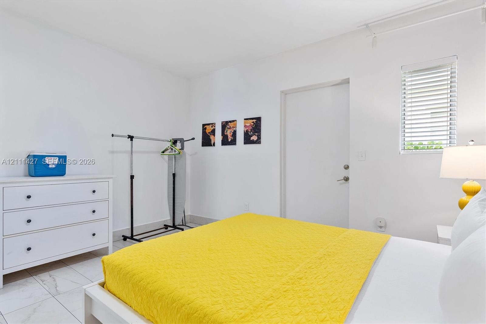 Neutral walls, white tile flooring, and a single window featuring horizontal blinds