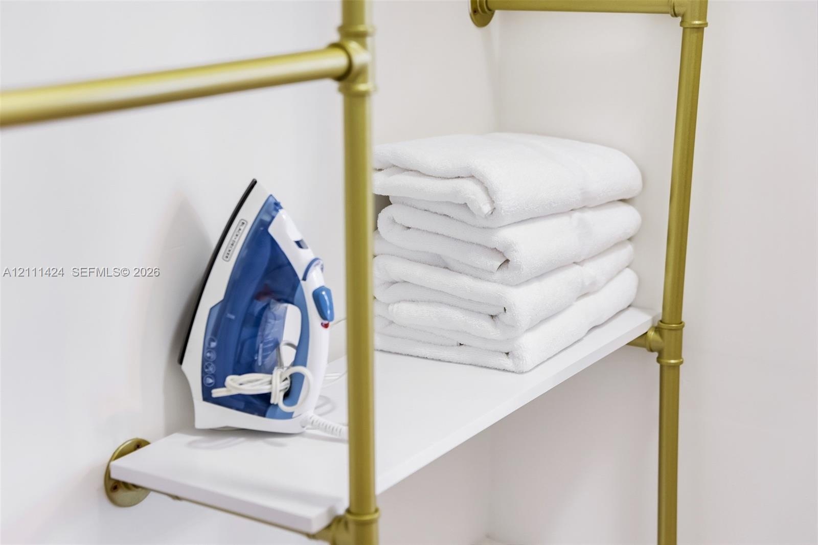 Wall-mounted storage unit featuring gold-tone metallic piping and white shelving