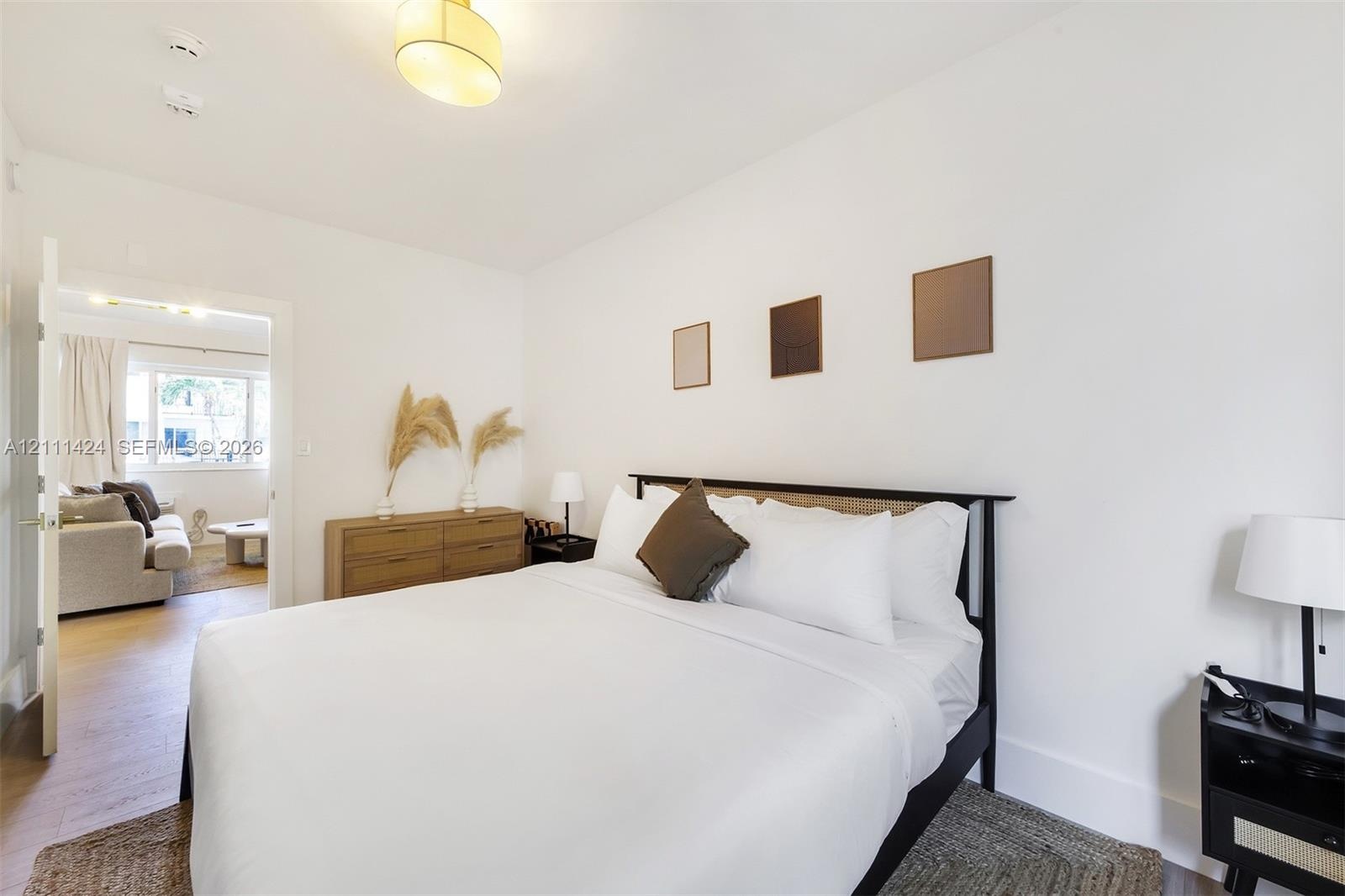 Neutral interior featuring light-toned wood-finish flooring, crisp white wall finishes, and a contemporary semi-flush mount ceiling fixture