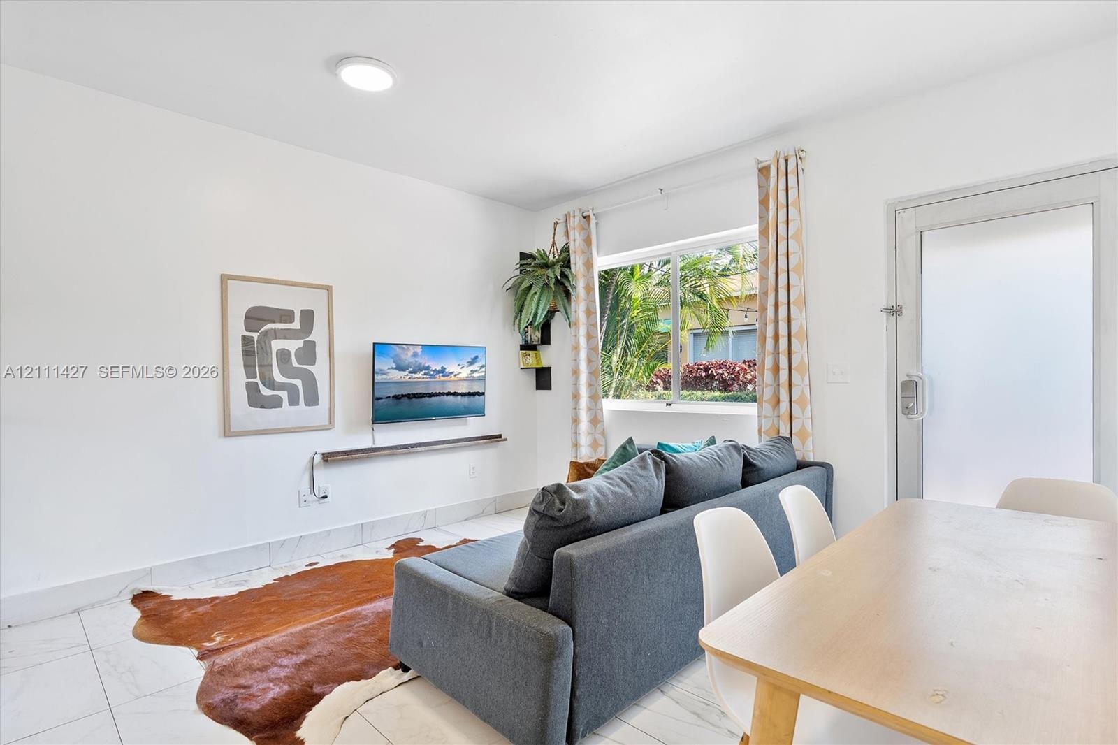 Neutral-toned interior featuring large-format tile flooring, a horizontal wall-mounted floating shelf, a multi-pane sliding window, and a glass-panele