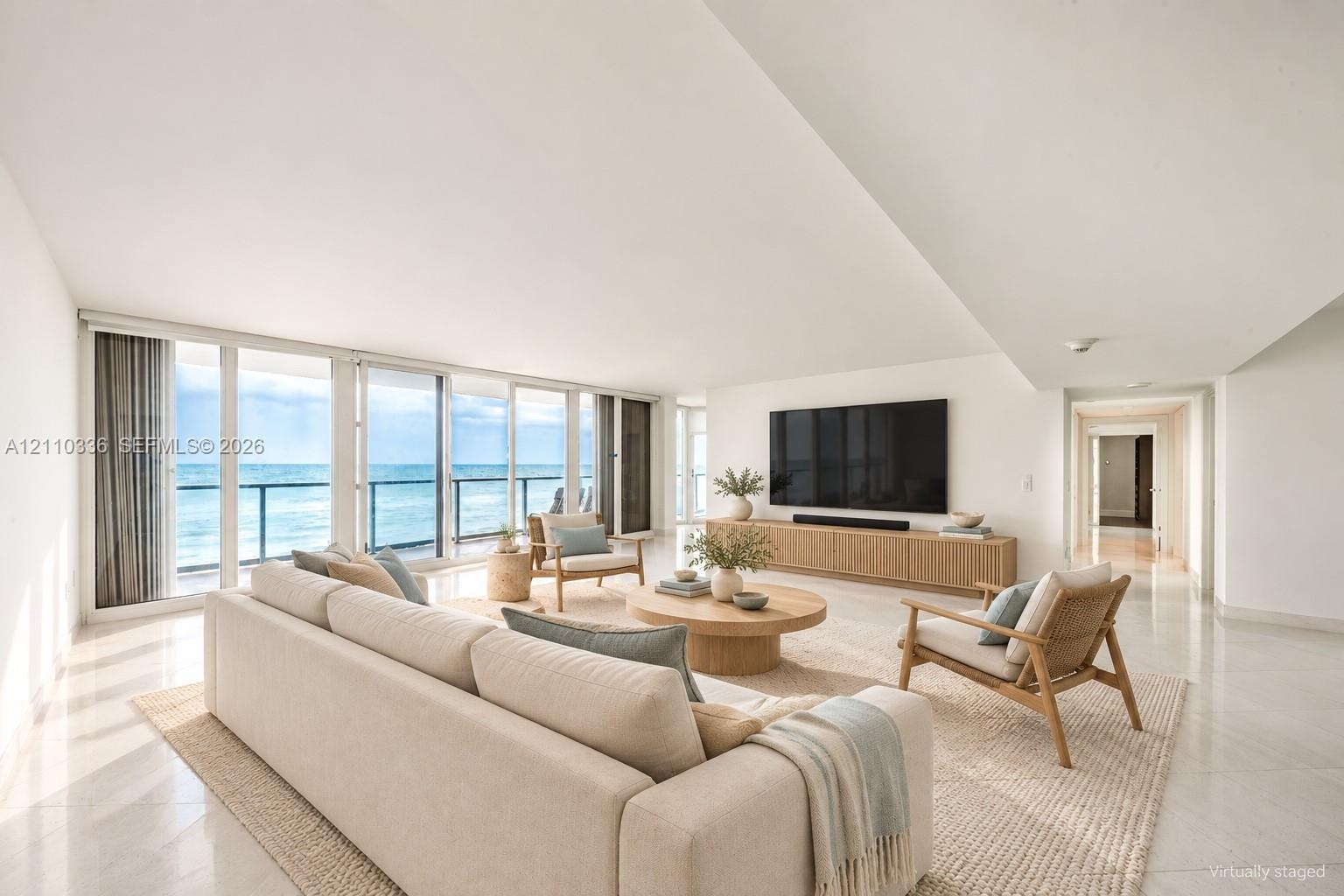 Expansive living space featuring floor-to-ceiling glass panel doors, a balcony with a metal railing, polished stone flooring, and a built-in wood-fini