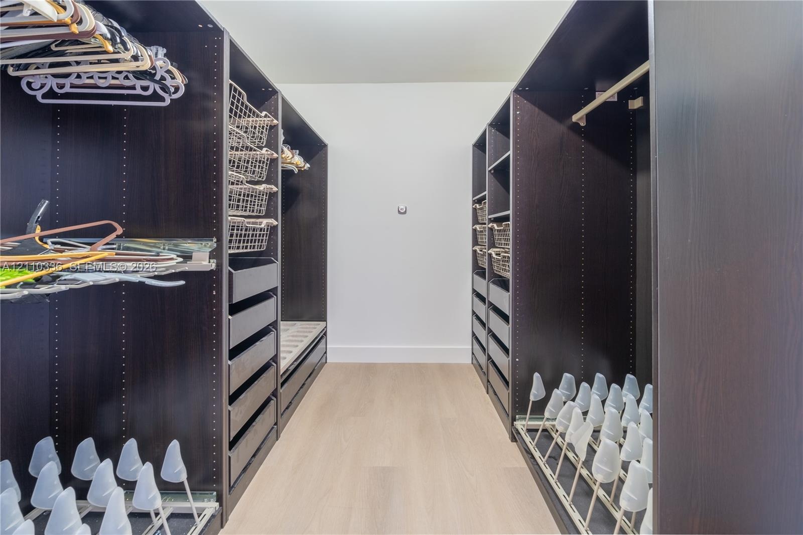 Custom closet featuring dark wood-finish cabinetry, built-in drawer units, integrated wire shelving, and slide-out shoe storage racks