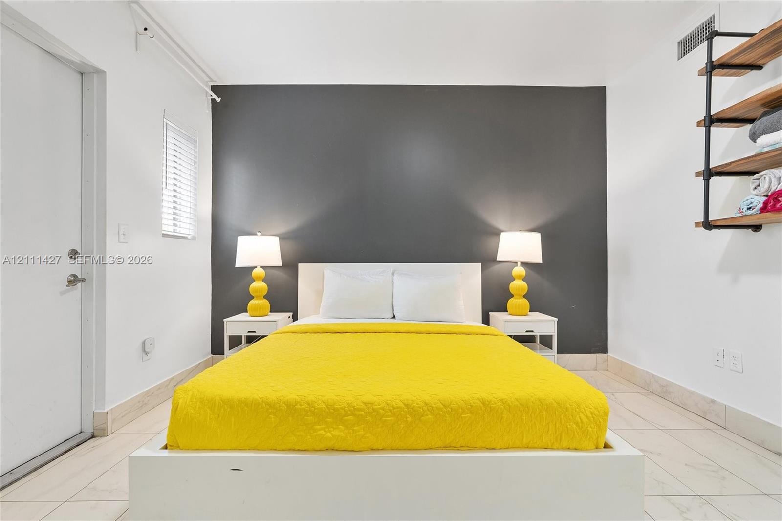 Room with a charcoal accent wall, tile flooring, and industrial-style wall-mounted shelving featuring wood-finish tiers and matte black metal piping