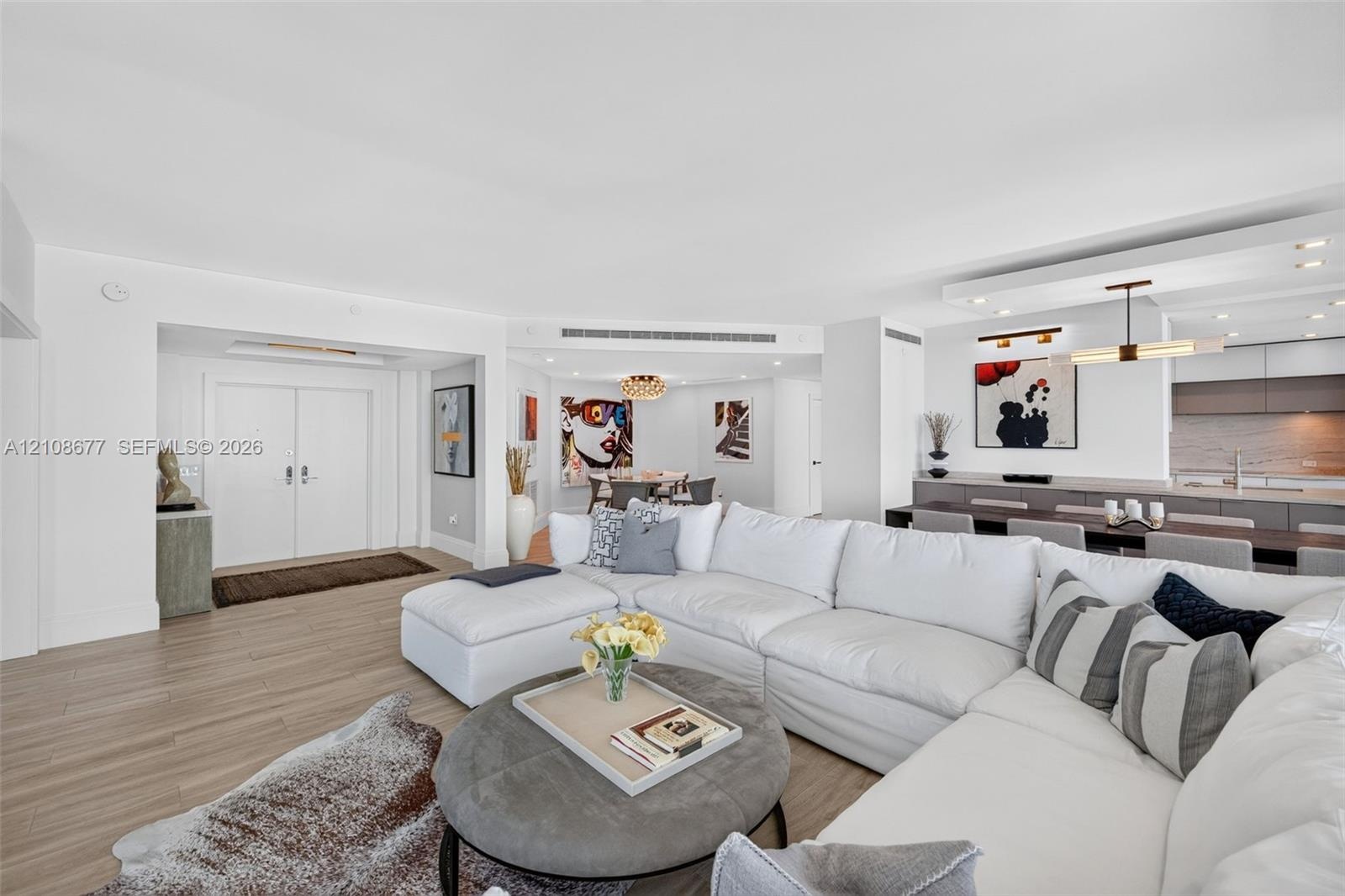 Open floor plan featuring wood look plank porcelain flooring, recessed lighting, double-door entry / foyer, and view toward the kitchen and stone wall