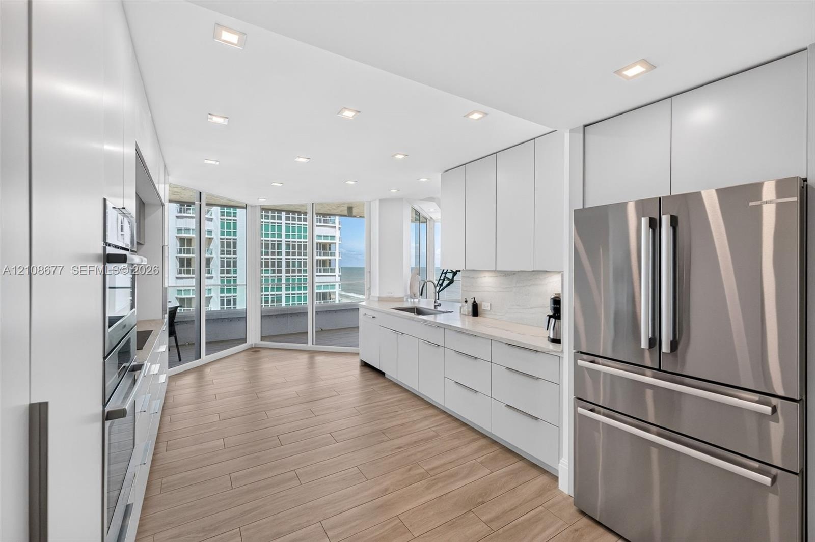 Contemporary updated top of the line kitchen featuring flat-panel white cabinets, stainless Bosch appliances (Miele dishwasher), integrated wall ovens