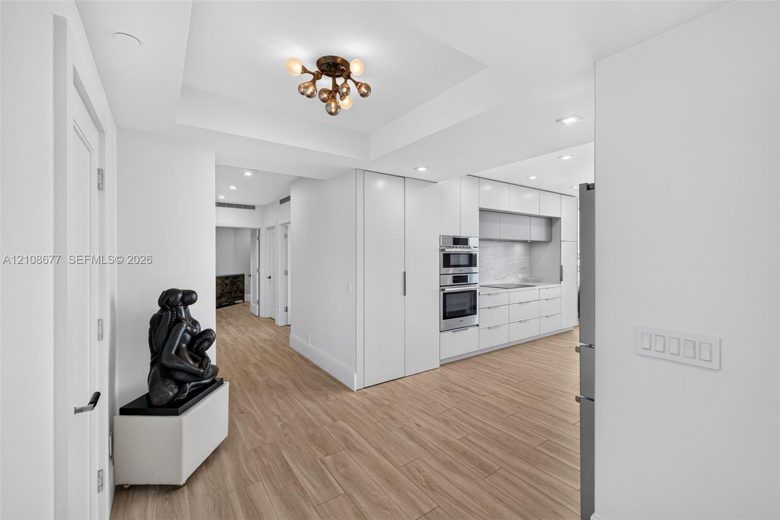 Widened hallway with primary bedroom straight down the hall, second bedroom next to it, plus gorgeous modern kitchen featuring white flat-panel cabine