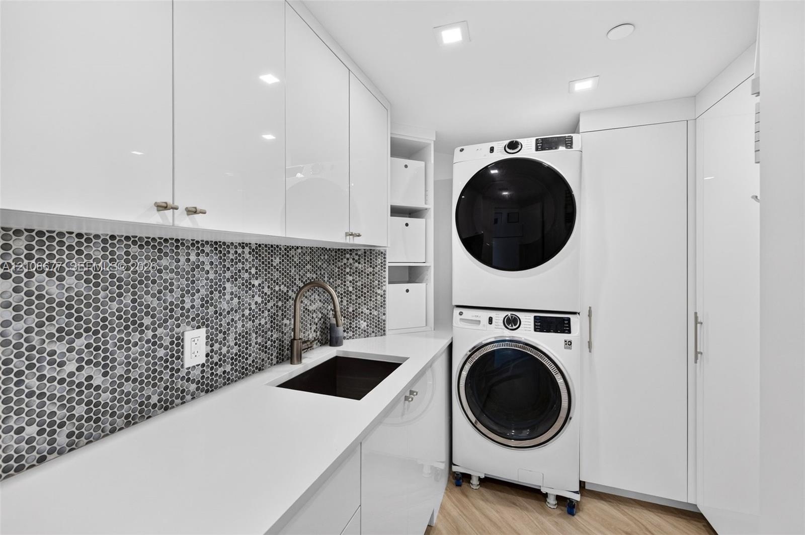 Expanded Laundry room featuring high-gloss cabinetry, quartz counters, mosaic penny-tile backsplash, an integrated basin sink with a gooseneck faucet,