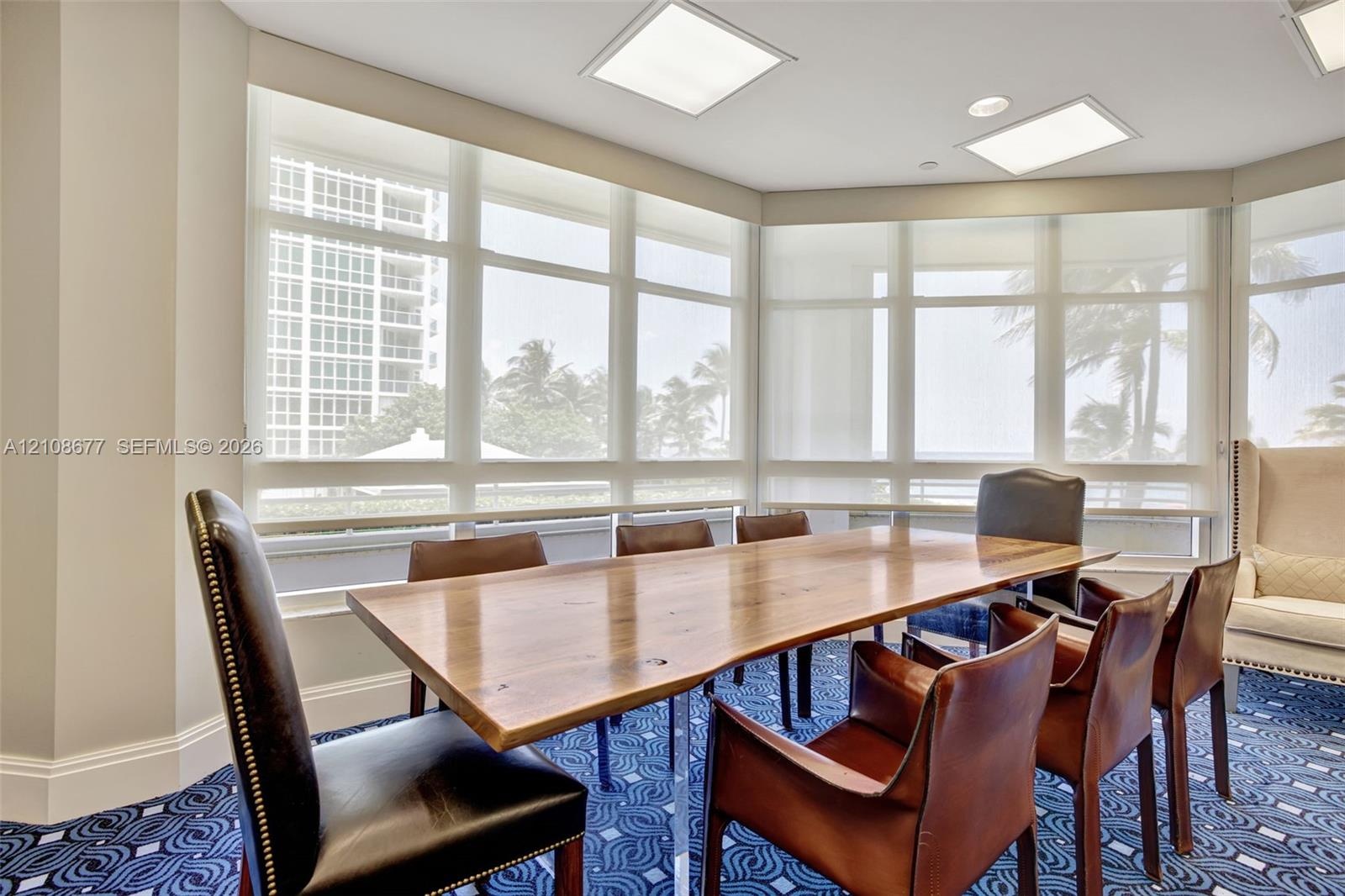 Building community room w/ dining table/ conference room area w/ floor-to-ceiling wrap-around windows featuring light-filtering roller shades and rece
