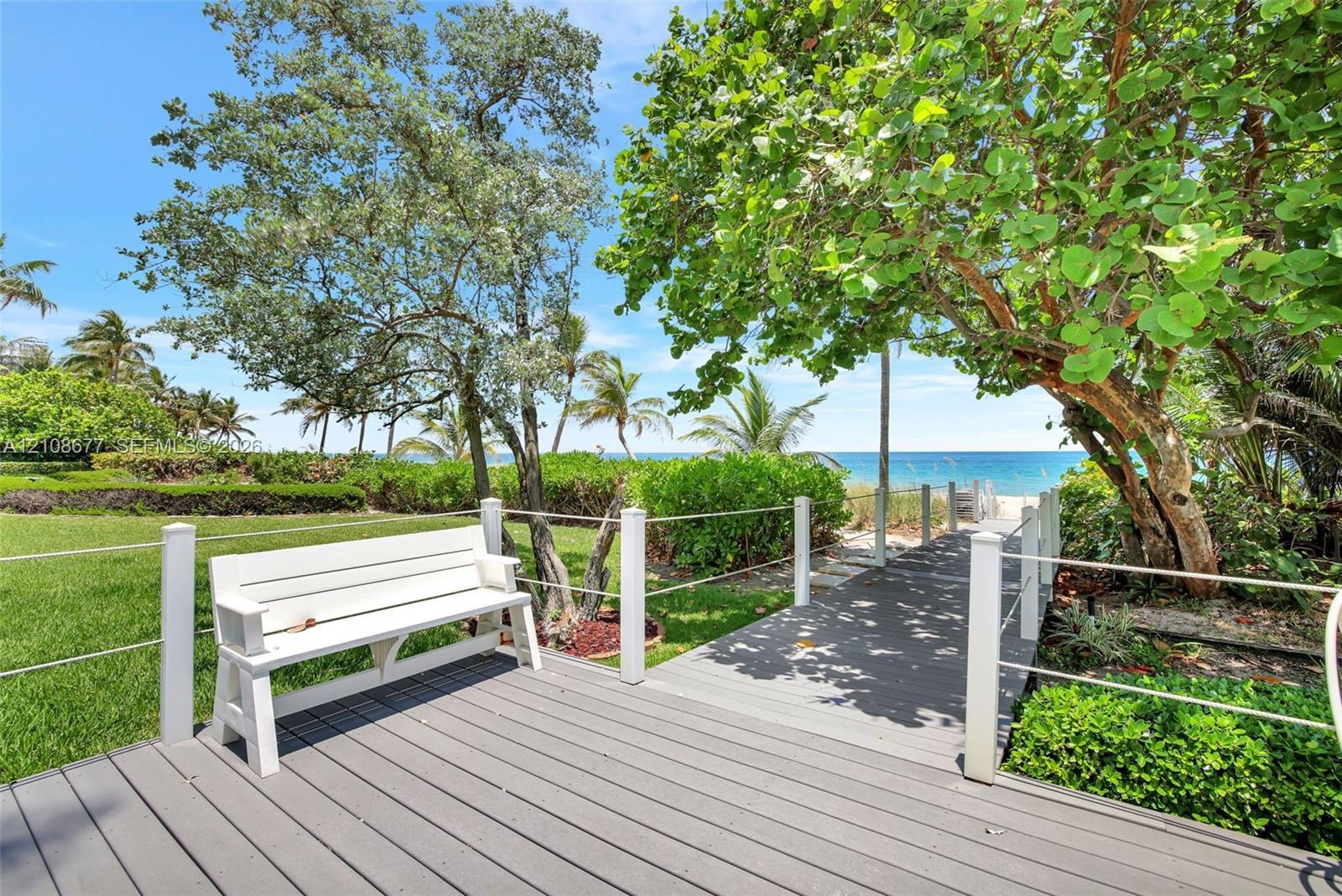 Elevated composite decking leads to mature coastal landscaping, and a direct path to the sandy oceanfront