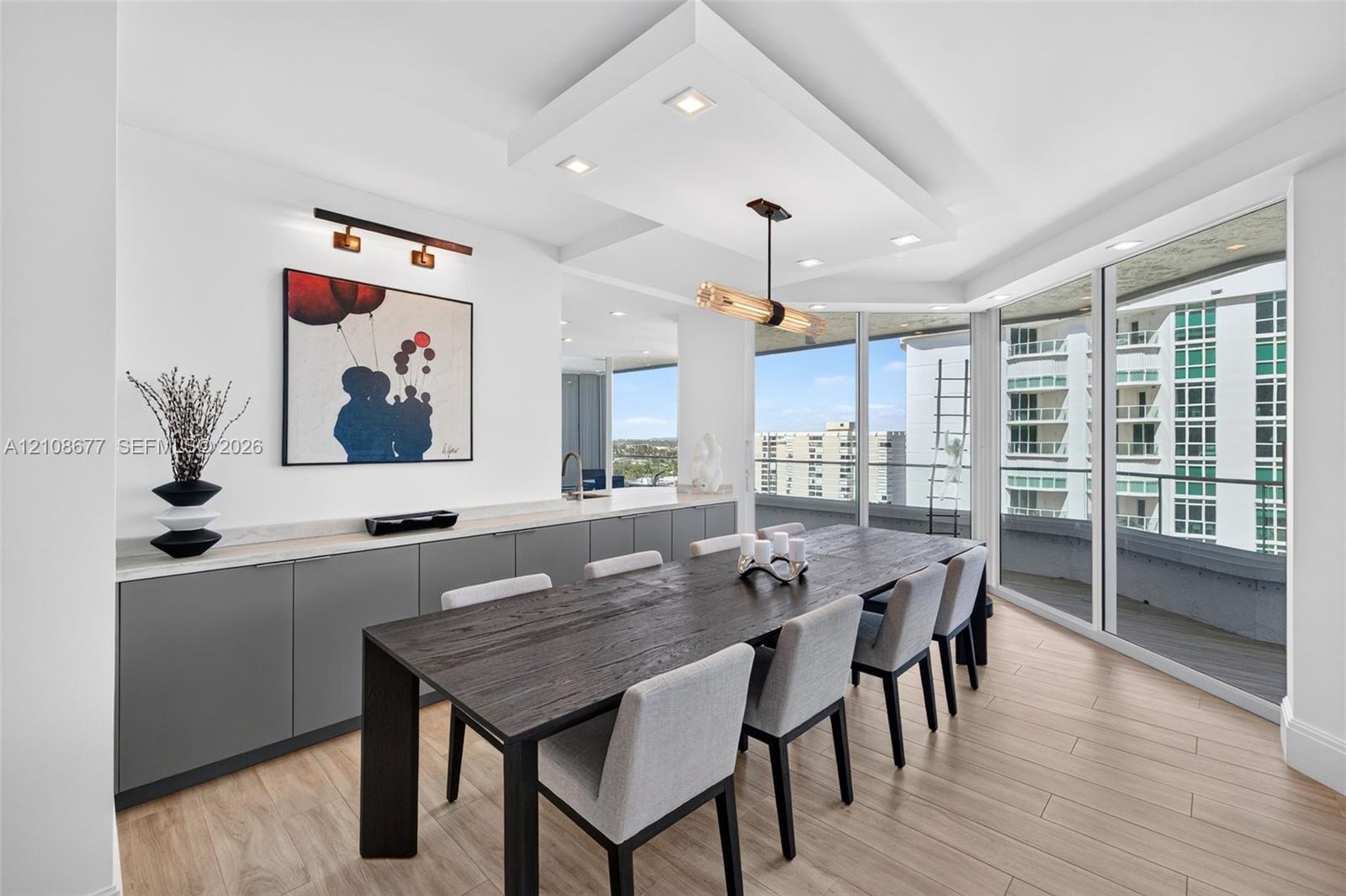 Floor-to-ceiling impact windows, recessed architectural ceiling detail with integrated lighting, wood look plank porcelain flooring, custom cabinets w