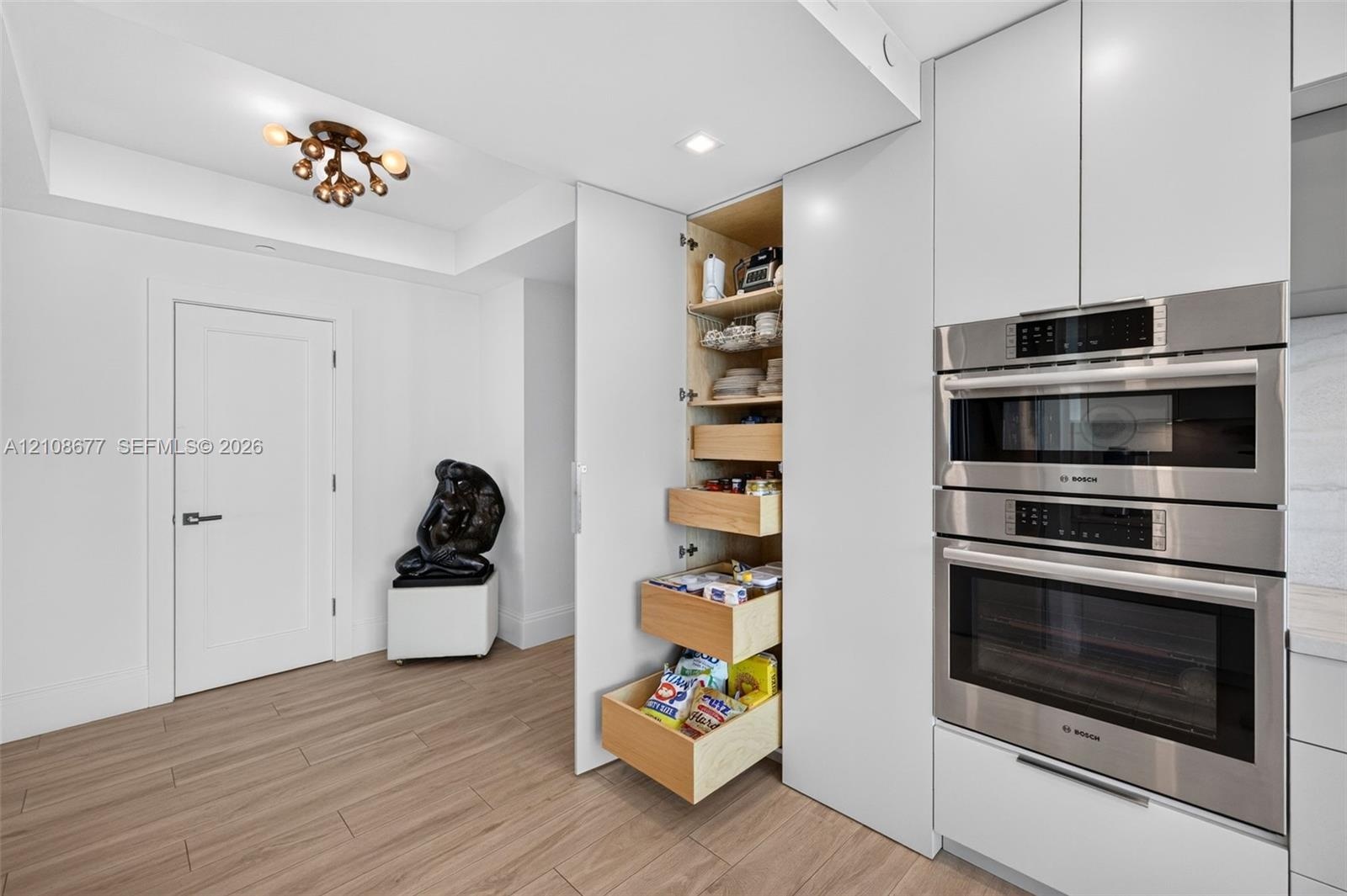 Custom cabinets featuring a floor-to-ceiling pull-out pantry with wood pull out and soft-close tongue & groove drawers, integrated stainless steel Bos