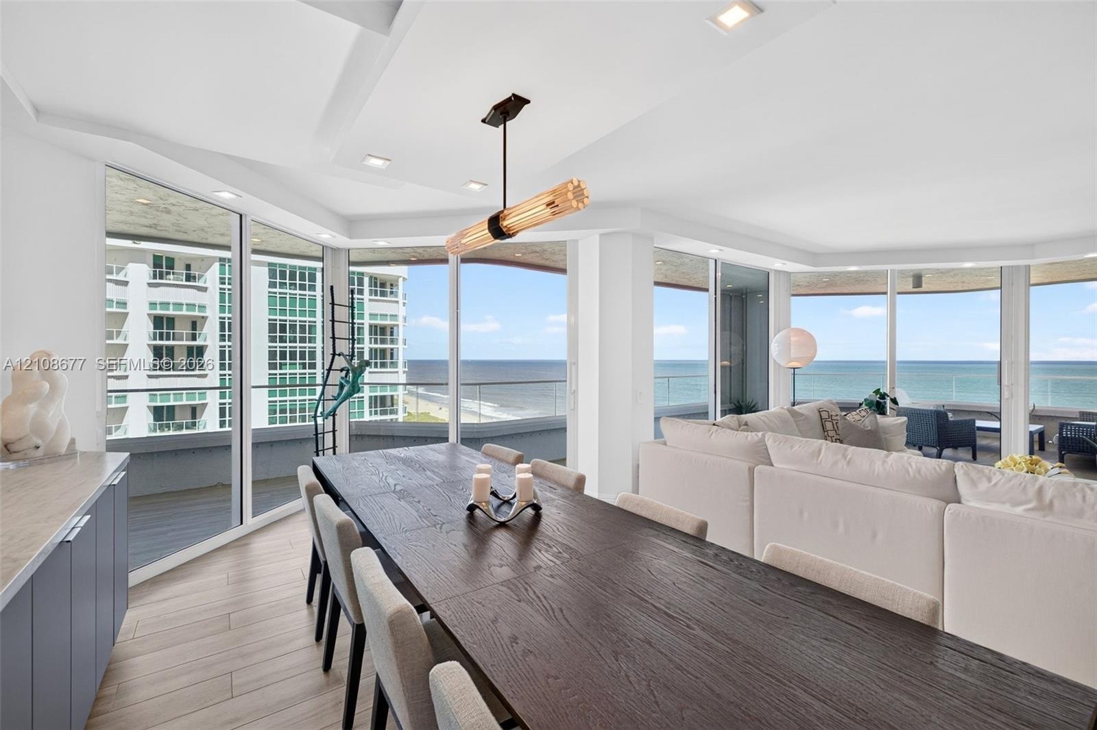 Floor-to-ceiling impact windows, wide-plank tile flooring, recessed lighting, contemporary linear light fixture, and wrap-around exterior balcony with