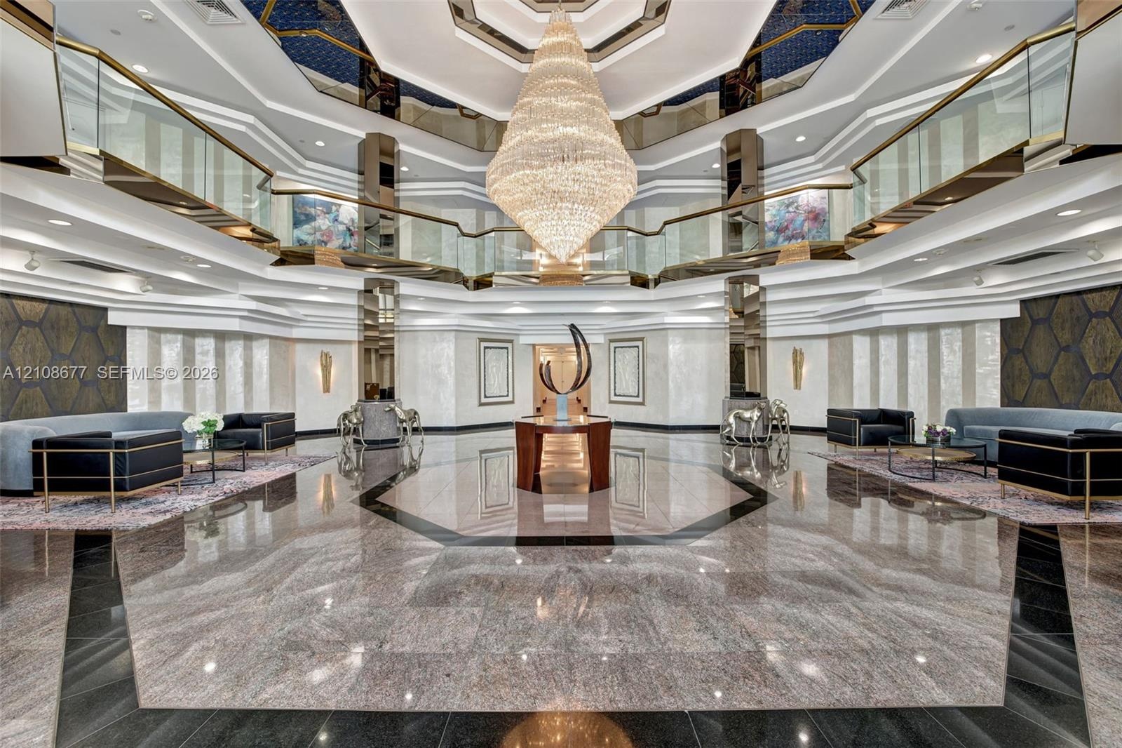 Grand lobby foyer featuring an expansive polished stone floor, a suspended multi-tiered crystal chandelier, a multi-faceted coffered ceiling with rece