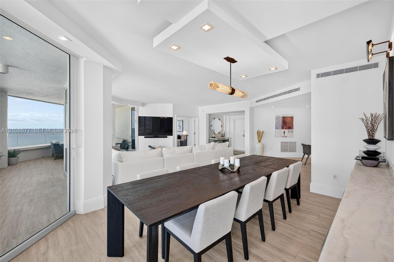 Open-concept interior featuring wood look plank porcelain flooring, recessed lighting, a custom architectural ceiling, a modern linear chandelier, and