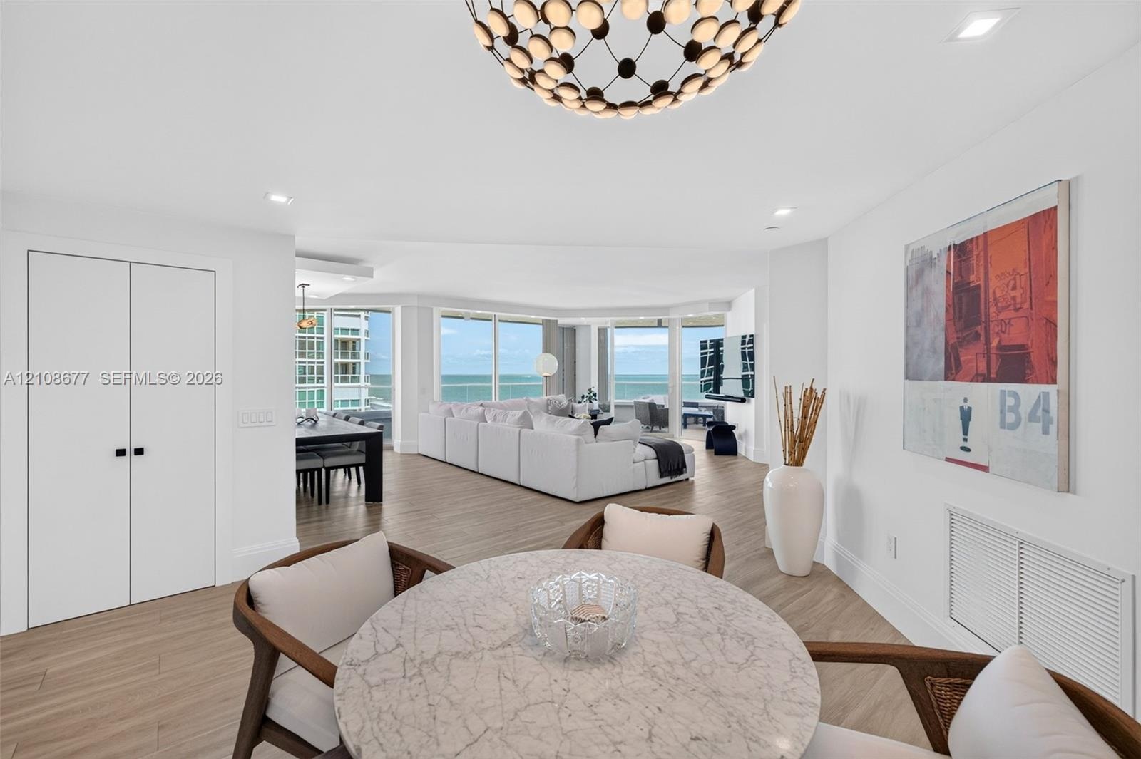 Open-concept informal dining or office space featuring wood look plank porcelain flooring, views toward the living room area, floor-to-ceiling windows