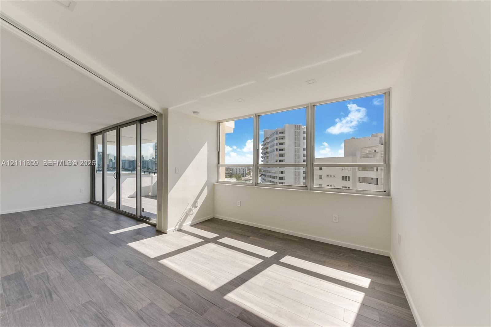 Open-concept interior featuring wood-finish flooring, floor-to-ceiling windows, recessed lighting, and sliding glass doors