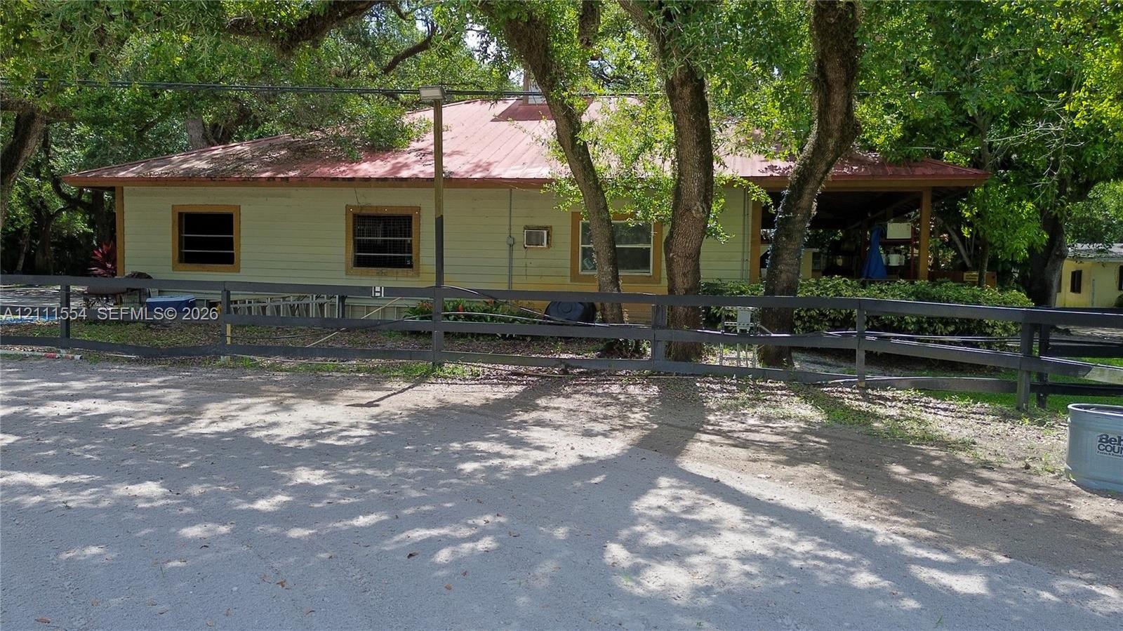 Exterior featuring horizontal siding, a metal roof, a covered porch, and a black split-rail fence
