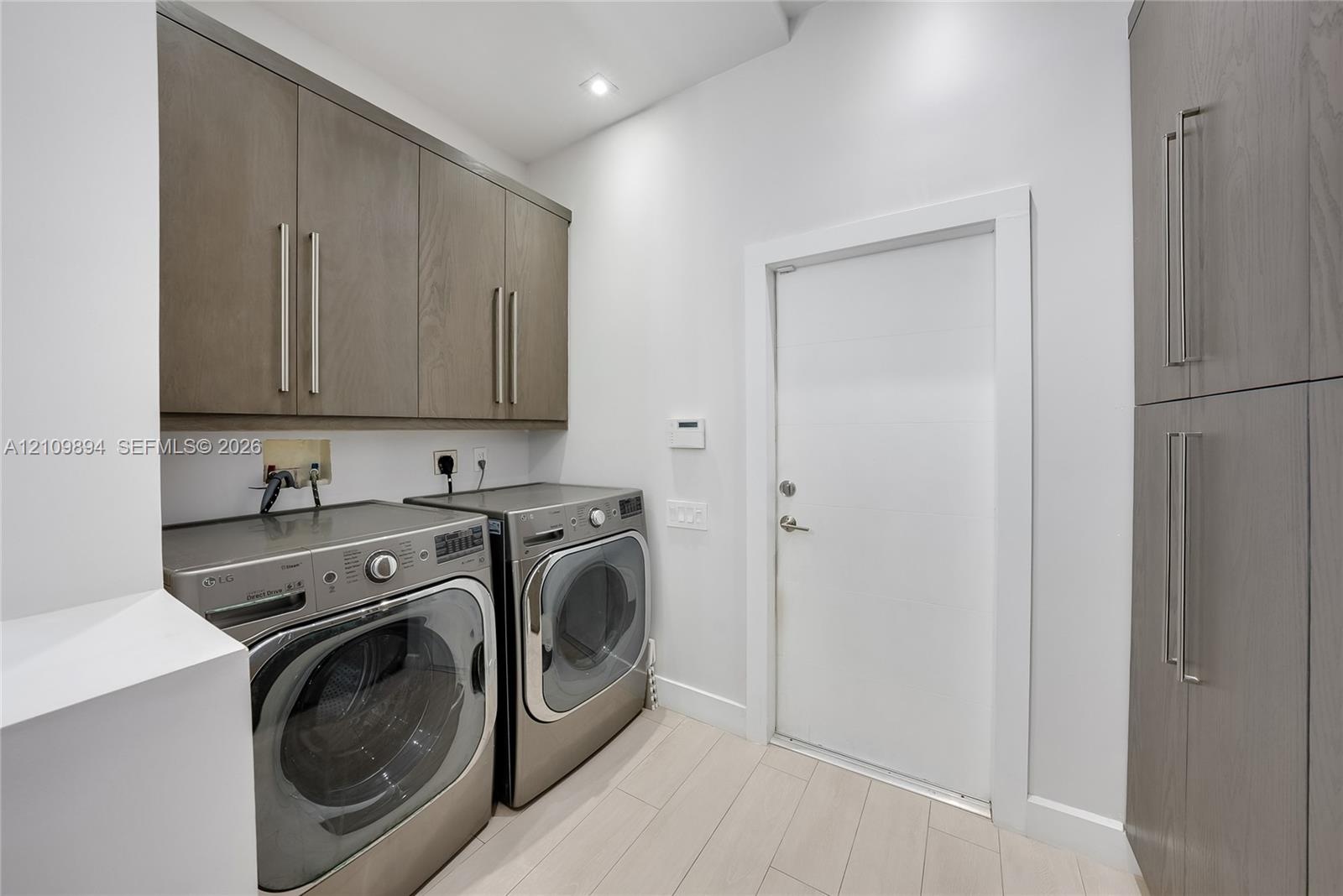 Laundry space featuring wood-finish cabinetry, floor-to-ceiling storage, wood-finish flooring, and recessed lighting
