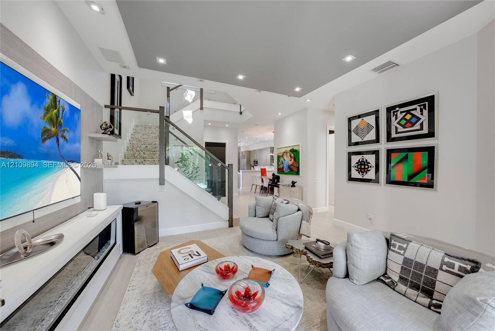 Interior space featuring recessed lighting, a built-in media console with linear fireplace, and a staircase with glass panel railing and dark finish h