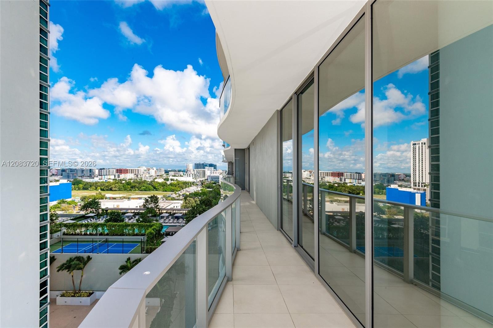 Expansive curved balcony featuring floor-to-ceiling glass walls, sleek metal railings, and tile flooring