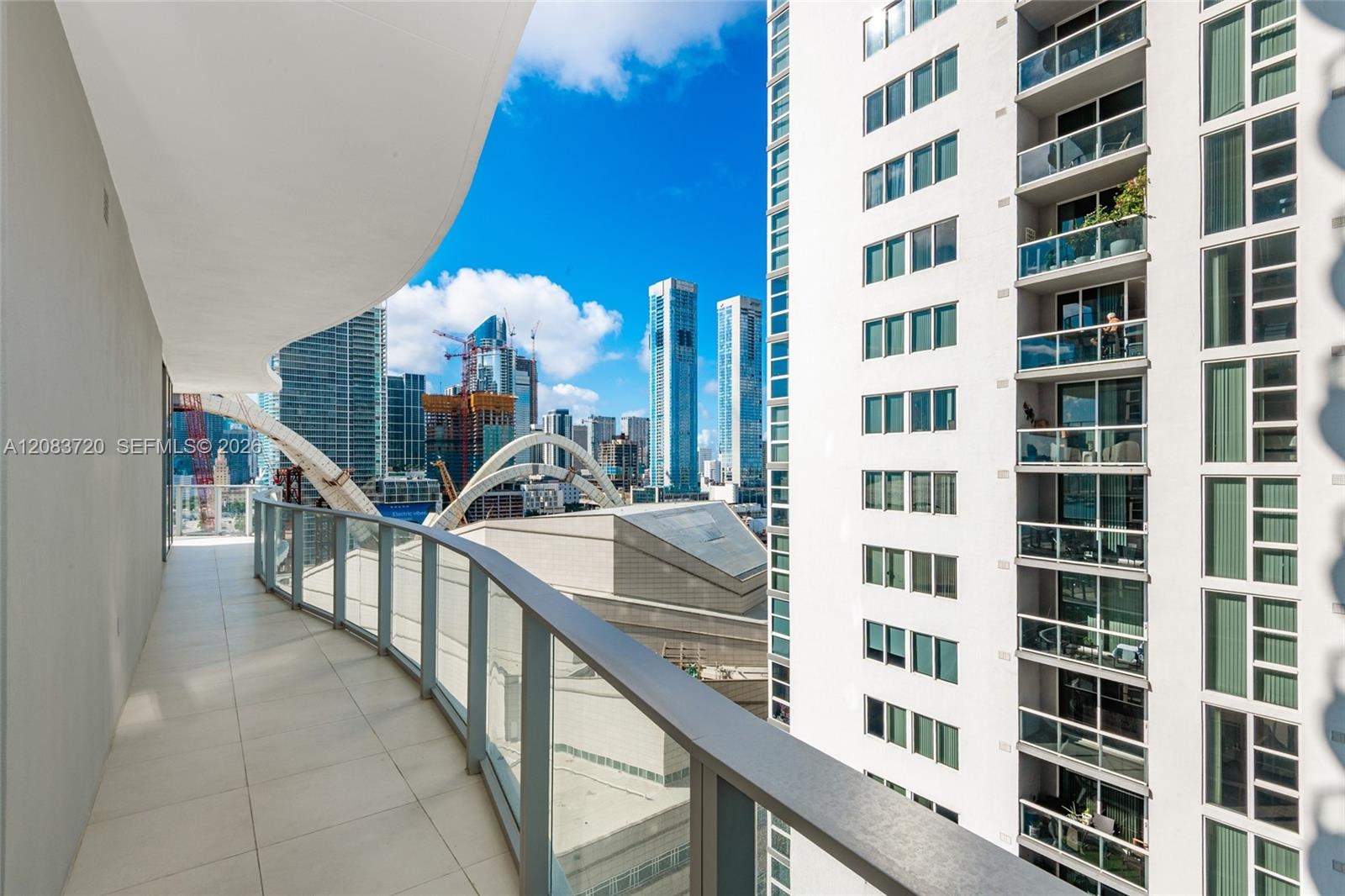 Curved balcony with large-format tile flooring and a glass-paneled railing