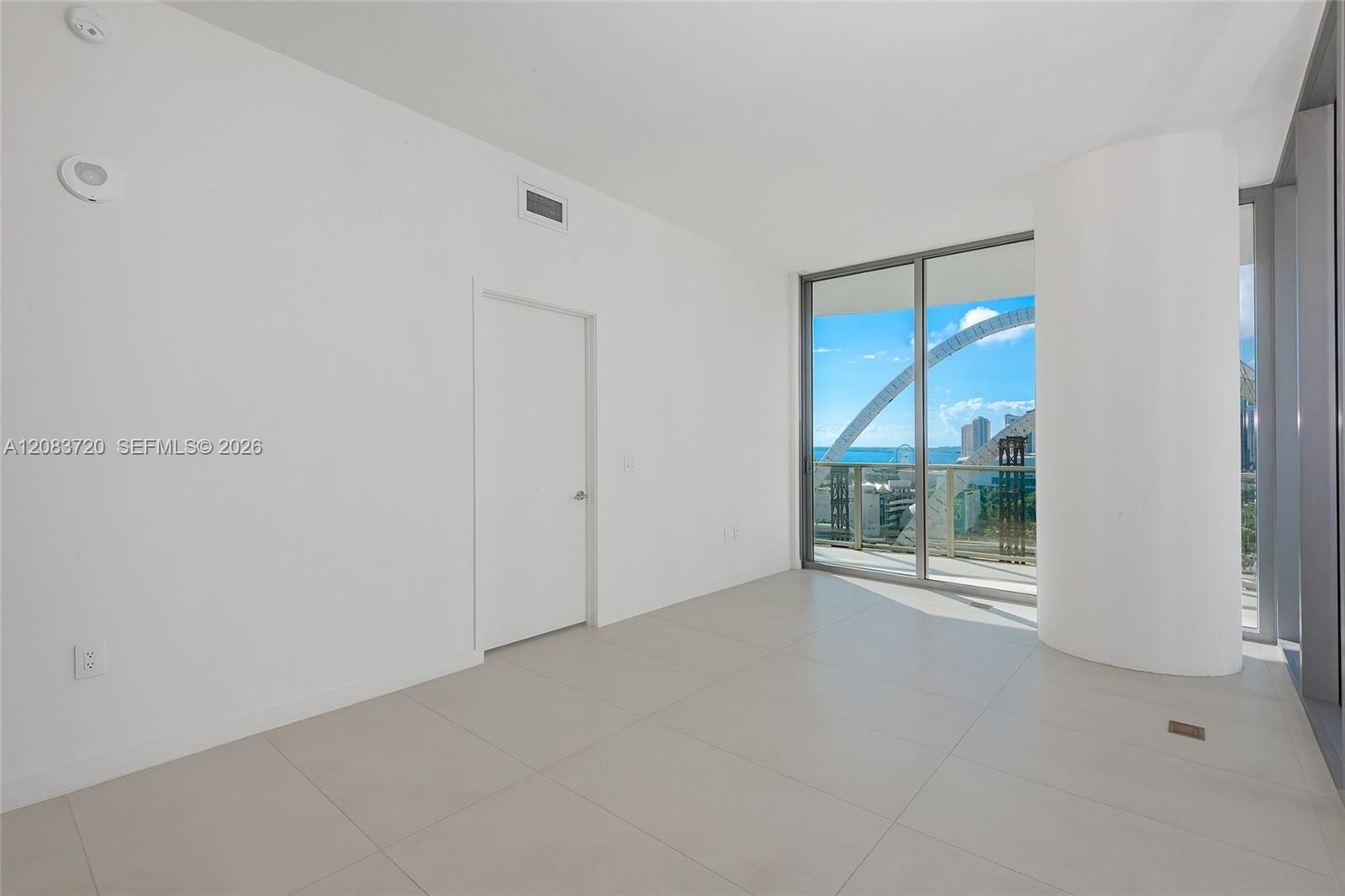 Interior space featuring large-format ceramic tile flooring, a prominent architectural cylindrical column, floor-to-ceiling glass sliding doors, and a