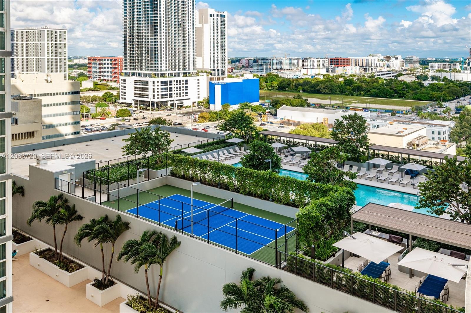 Rooftop recreation level featuring a pickleball court, swimming pool, structured landscaping, and covered lounge areas