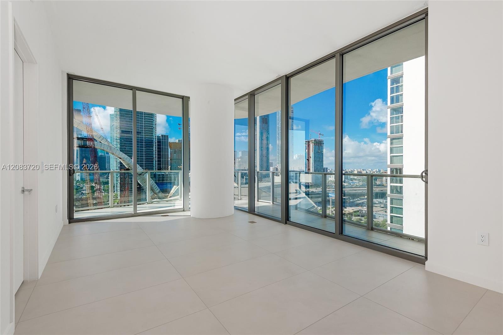 Floor-to-ceiling glass windows, expansive private balcony with glass railings, and light-toned large-format tile flooring