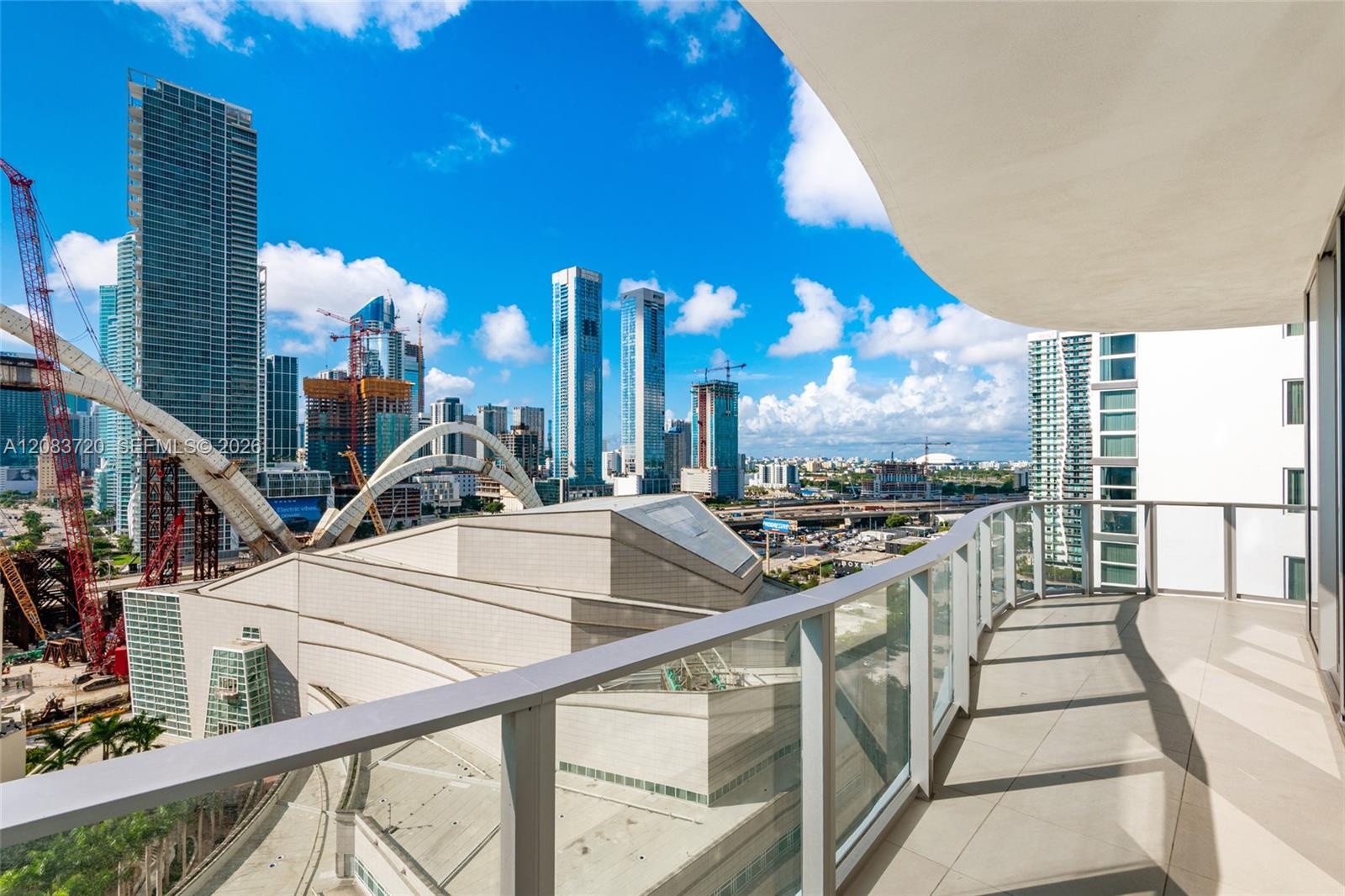 Curved exterior balcony featuring large-format tile flooring and glass panel railings