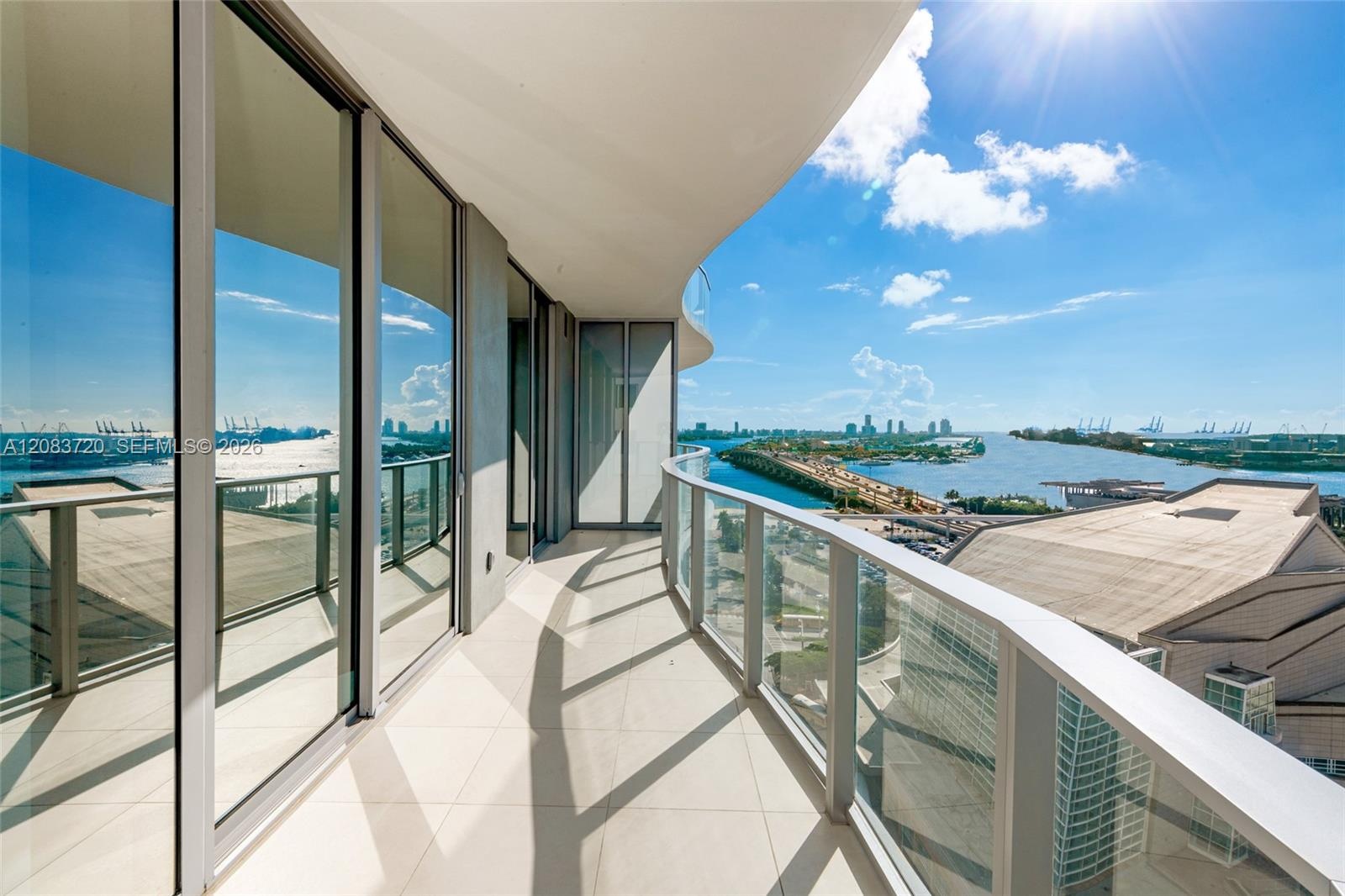 Curved exterior balcony featuring large-format tile flooring, floor-to-ceiling glass paneling, and a tempered glass railing