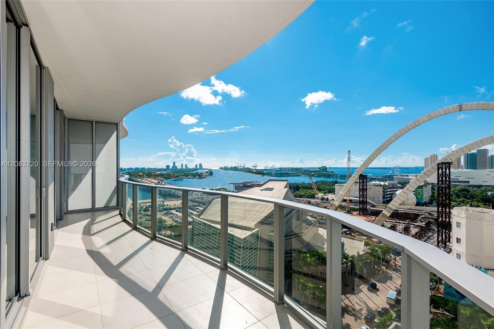 Curved, expansive balcony featuring large-format tile flooring and a glass-paneled railing