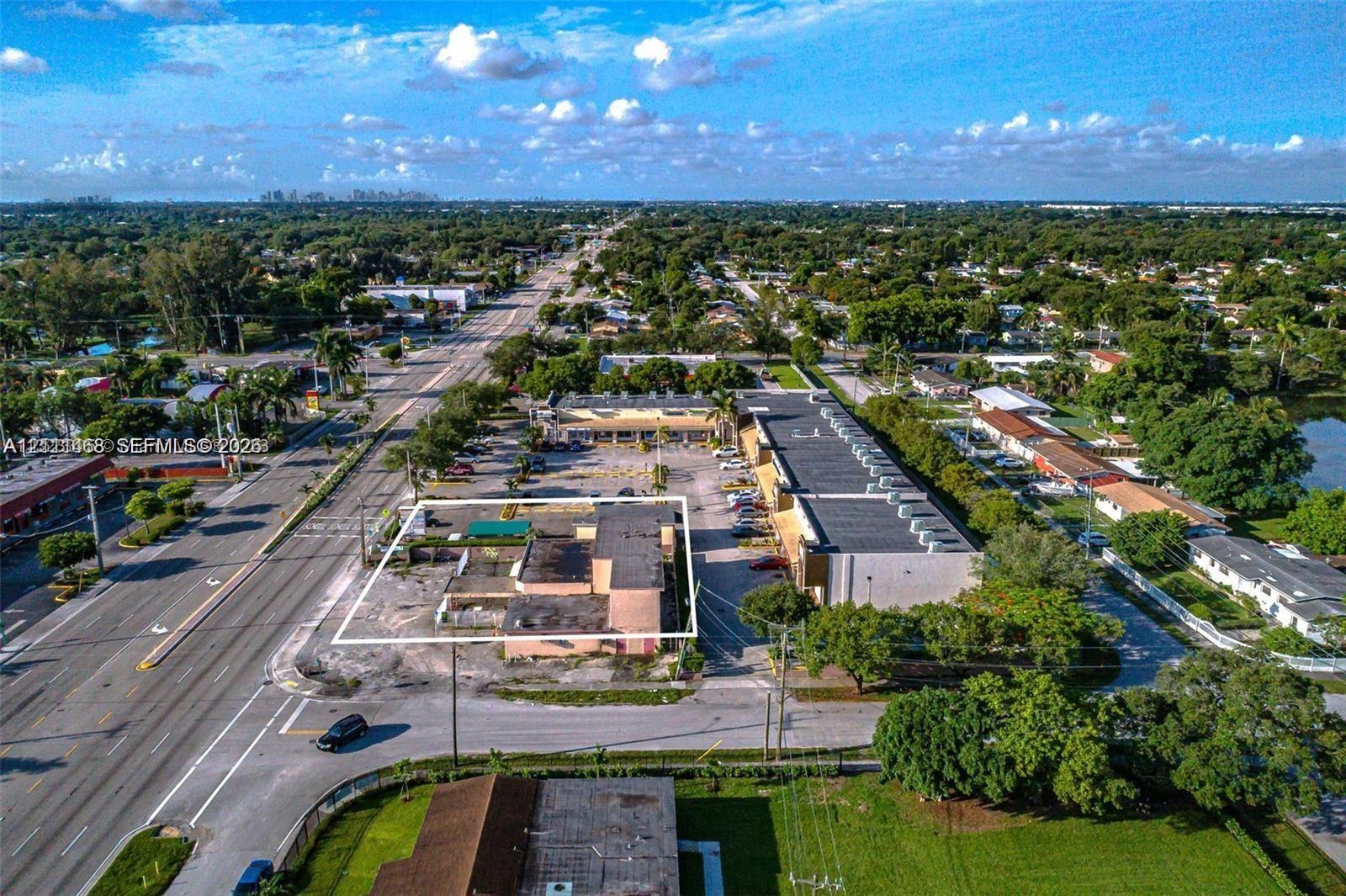 Aerial perspective of a corner lot property featuring frontage along a primary roadway, surface parking, and a single-story commercial structure