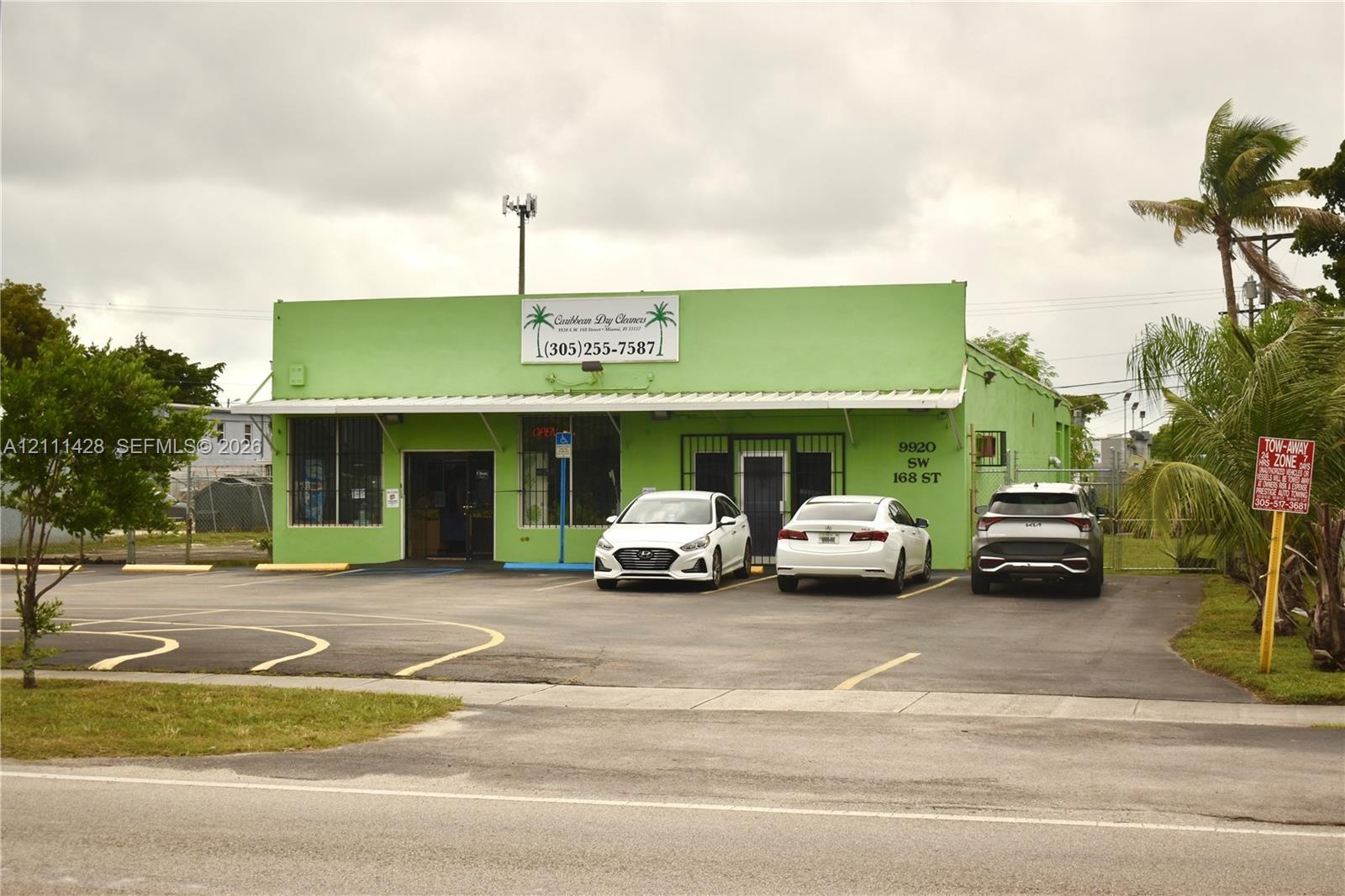 Commercial property featuring a concrete exterior, metal roof canopy, and asphalt parking area