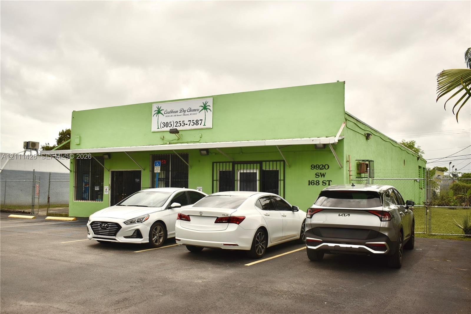 Commercial property exterior featuring a paved parking area, metal awning, and steel security window bars